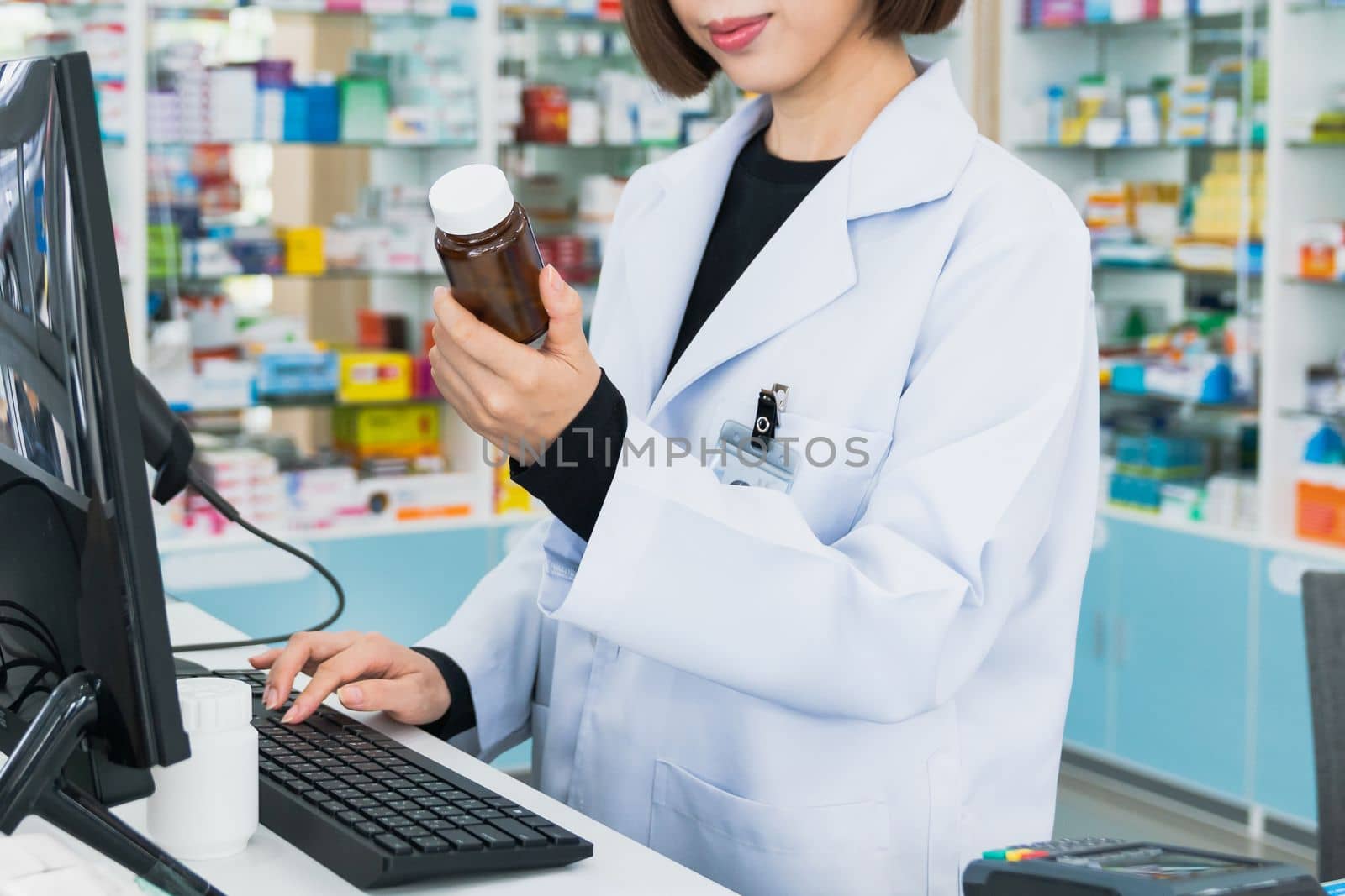 Closeup portrait of a young pharmacist and qualified pharmaceutical, medicine pill container or bottle mockup for copyspace at pharmacy. Drugstore concept with various medicine pills on