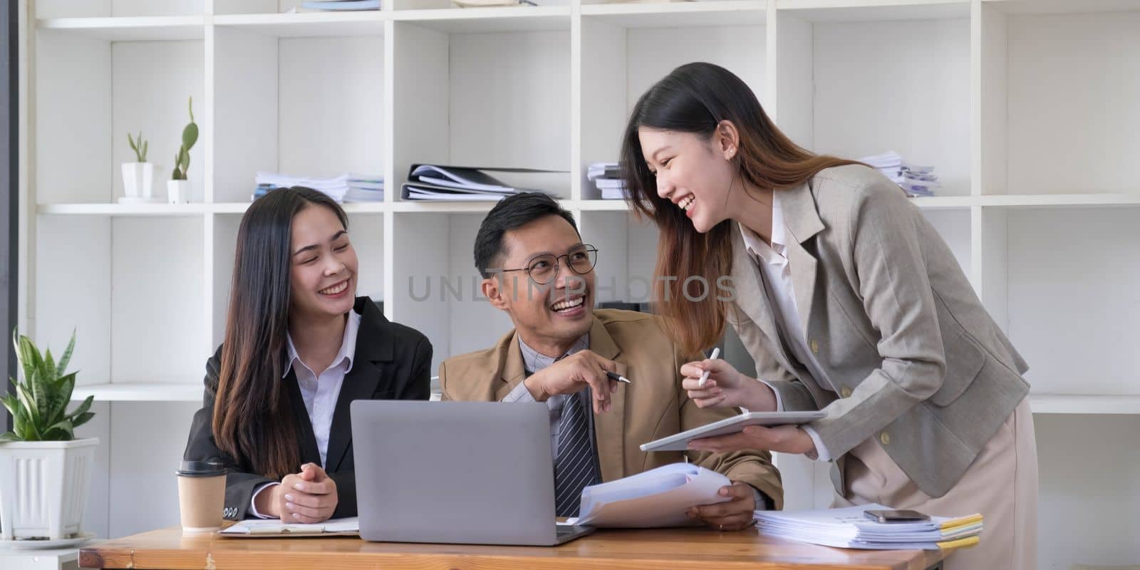 Group of young asian business people in smart casual wear working together in creative office using laptop...