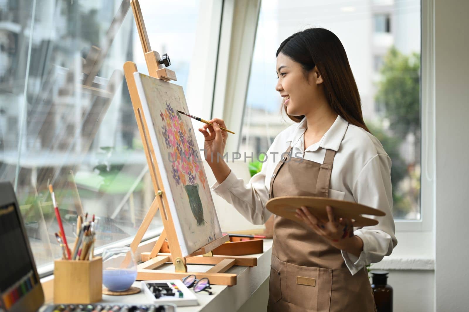 Beautiful asian woman painting picture with acrylic paints on canvas, enjoying creative leisure activities. Art and leisure activity concept.