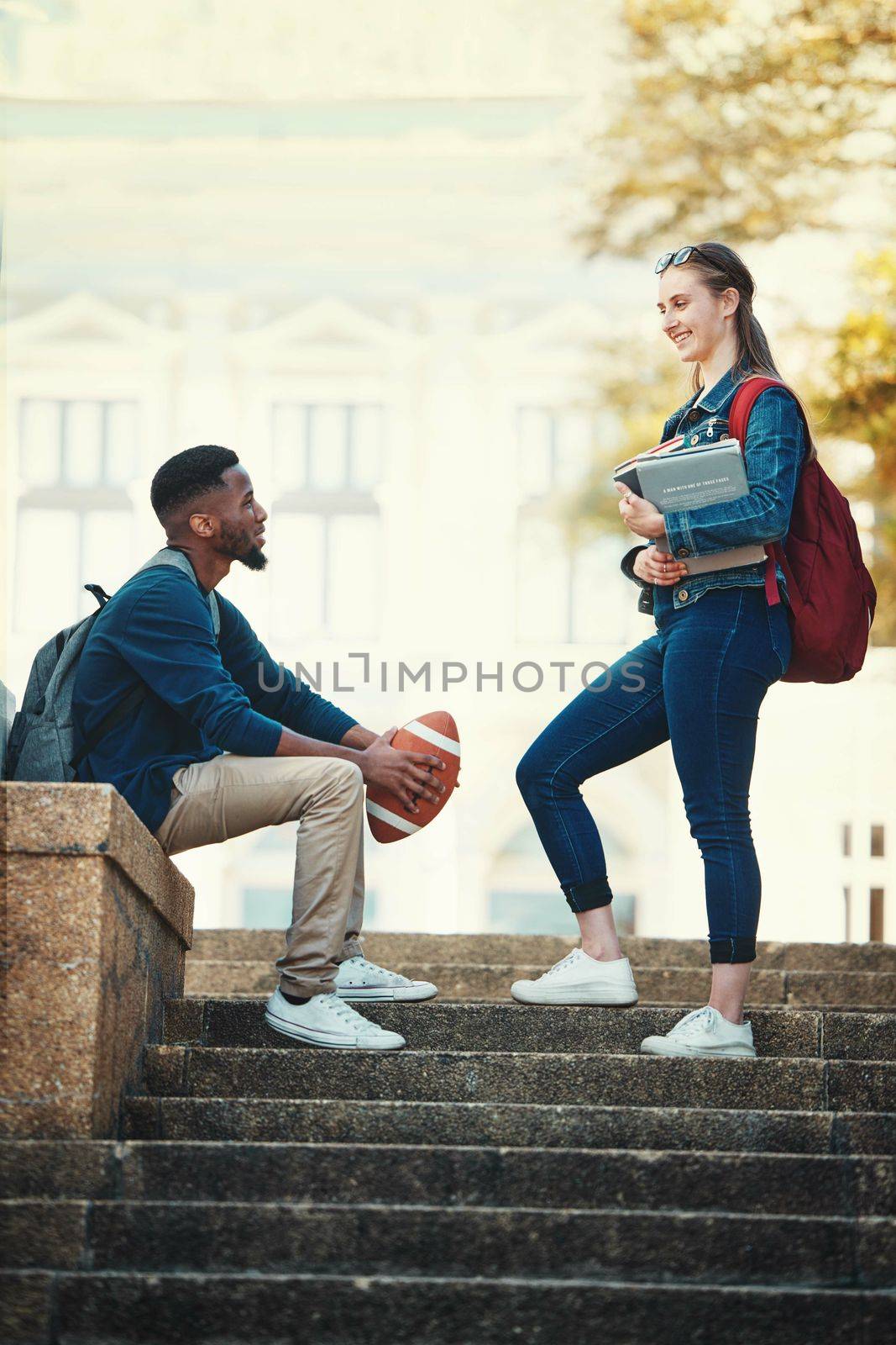 University, campus steps and students talking, speaking or discussion. Diversity, communication and friends, black man and woman in conversation about books, football sports or education and learning by YuriArcurs