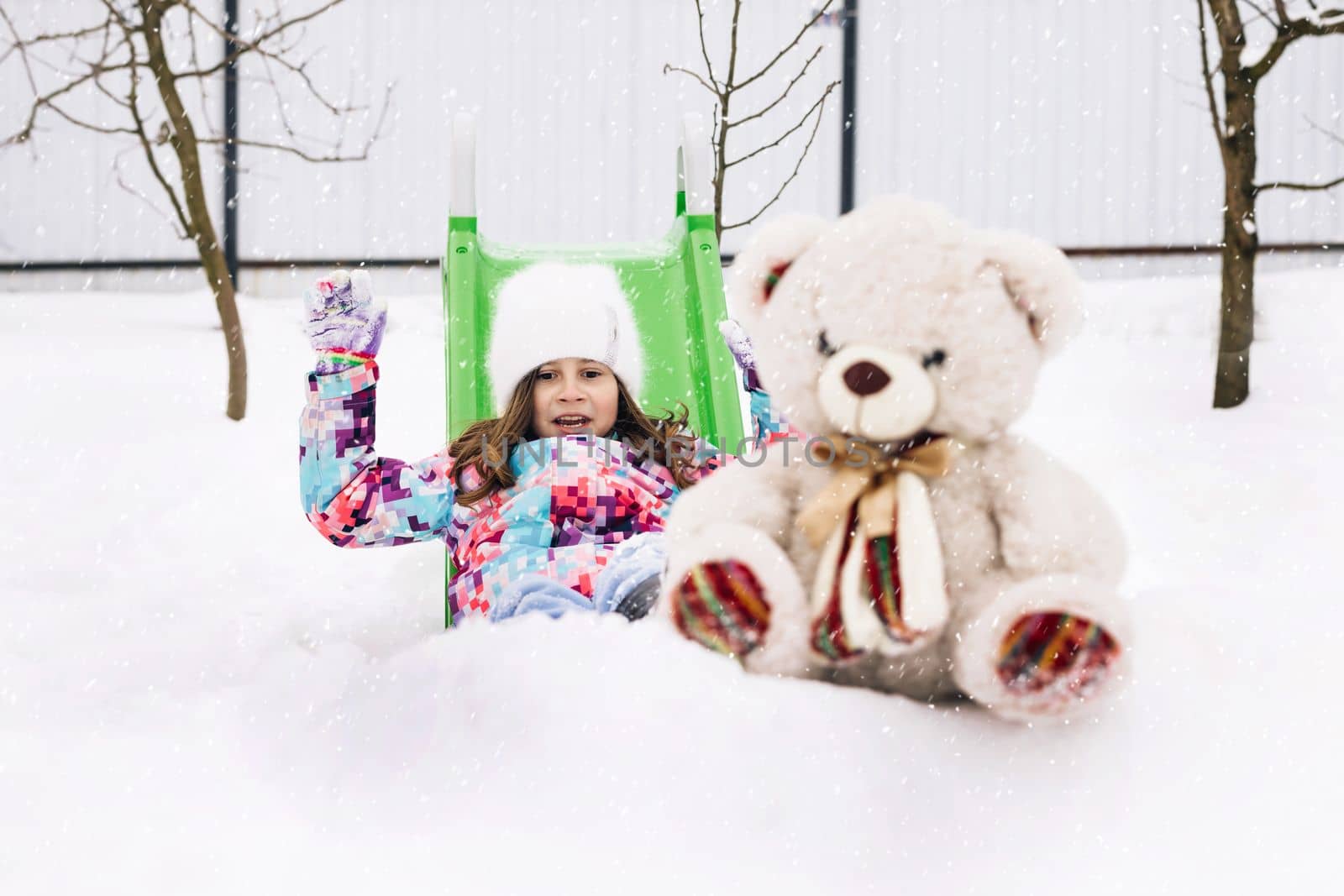 Cute toddler girl playing with teddy bear in winter park. Winter portrait of little caucasian child girl. Outdoor winter activities for kids.
