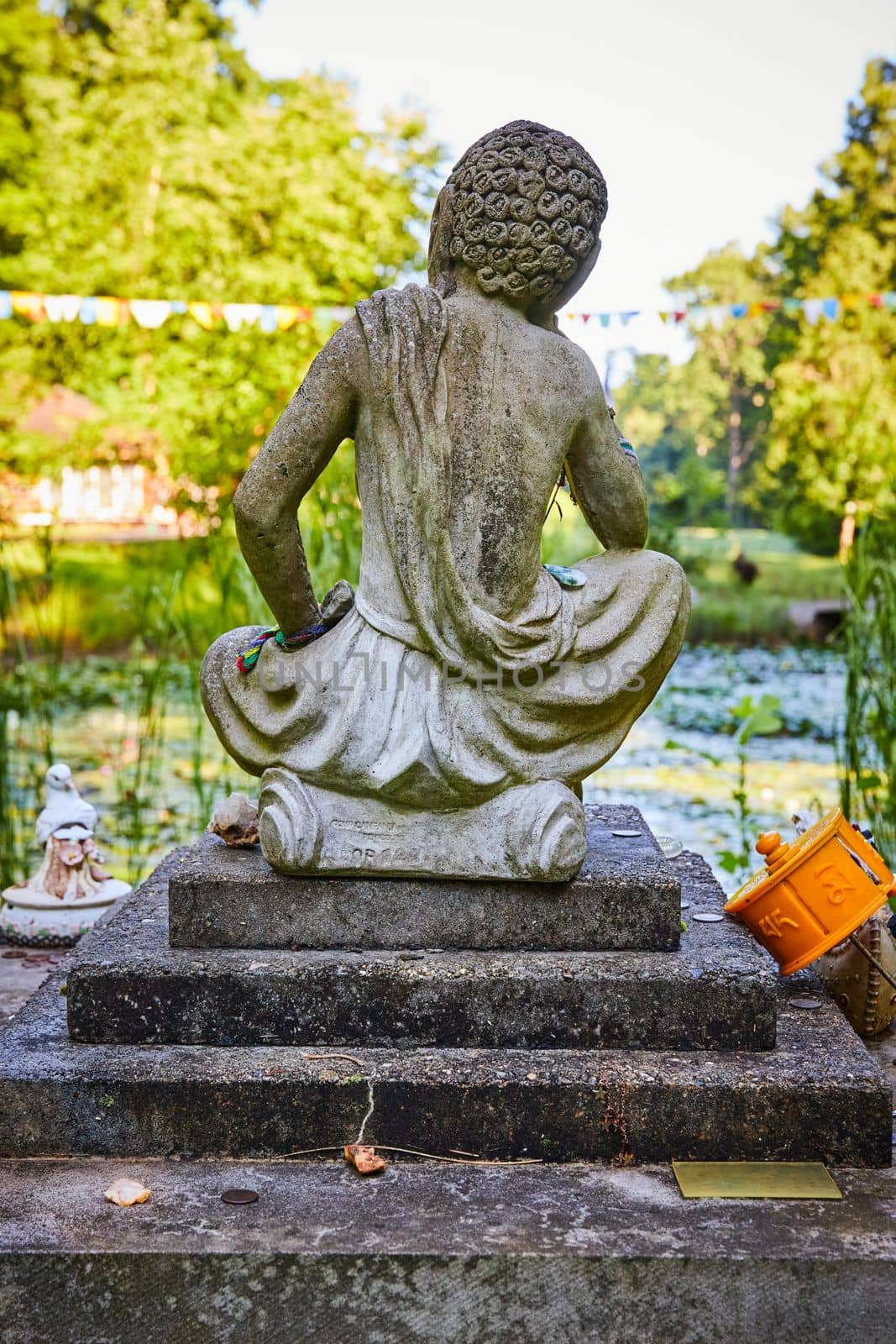 Image of Tibetan Mongolian Buddhist stone statue from behind overlooking lily pond