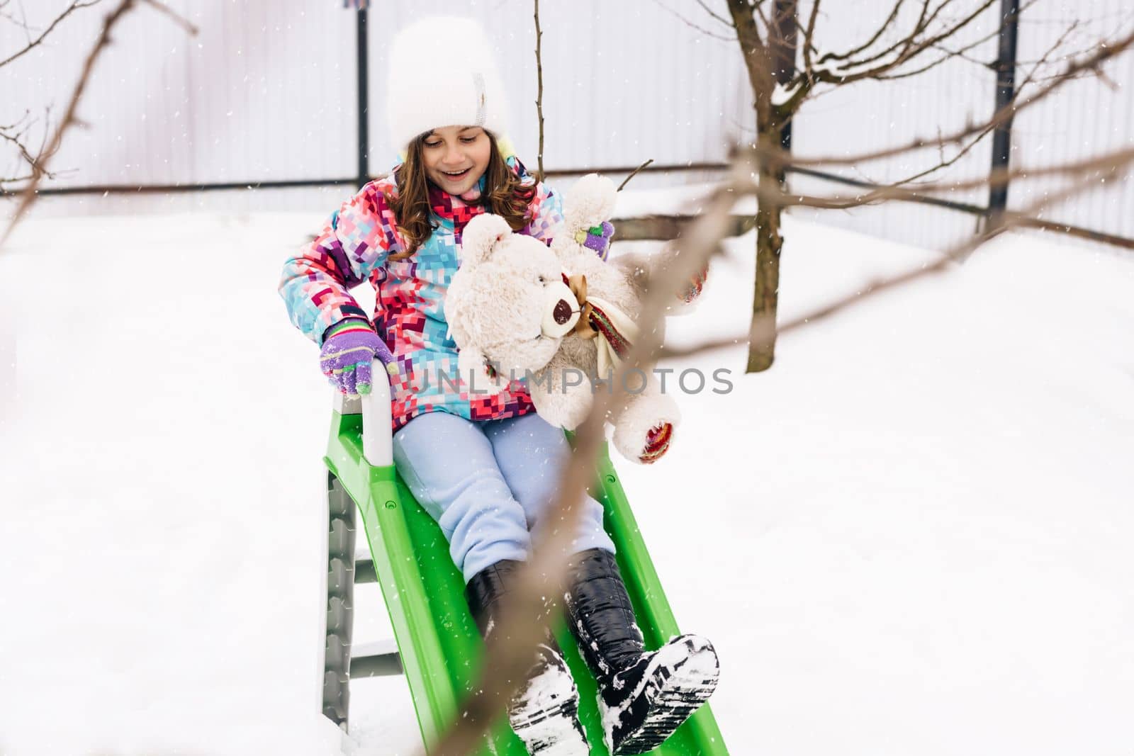 Child with toy teddy bear sits on a sled. Winter vacantion. Christmas celebration and winter holidays. Winter fun and outdoor activities with kids.