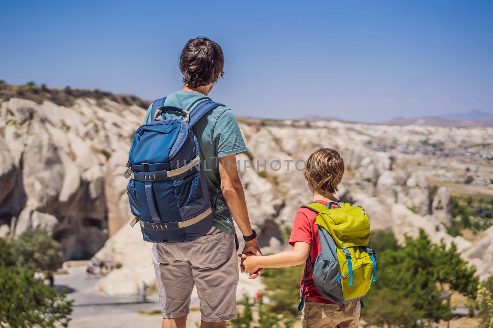 Father and son tourists exploring valley with rock formations and fairy caves near Goreme in Cappadocia Turkey.