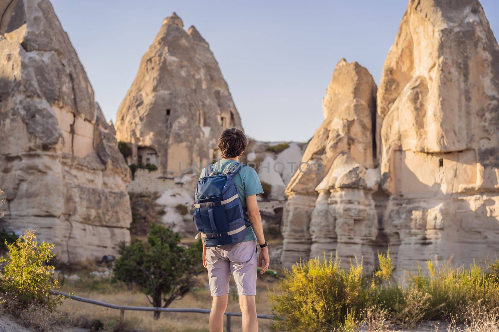 Man tourist on background of Unique geological formations in Love Valley in Cappadocia, popular travel destination in Turkey.