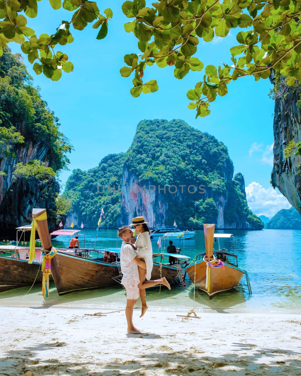 Koh Lao Lading near Koh Hong Krabi Thailand, a beautiful beach with longtail boats, a couple of European men, and an Asian woman on the beach. Couple on a boat trip