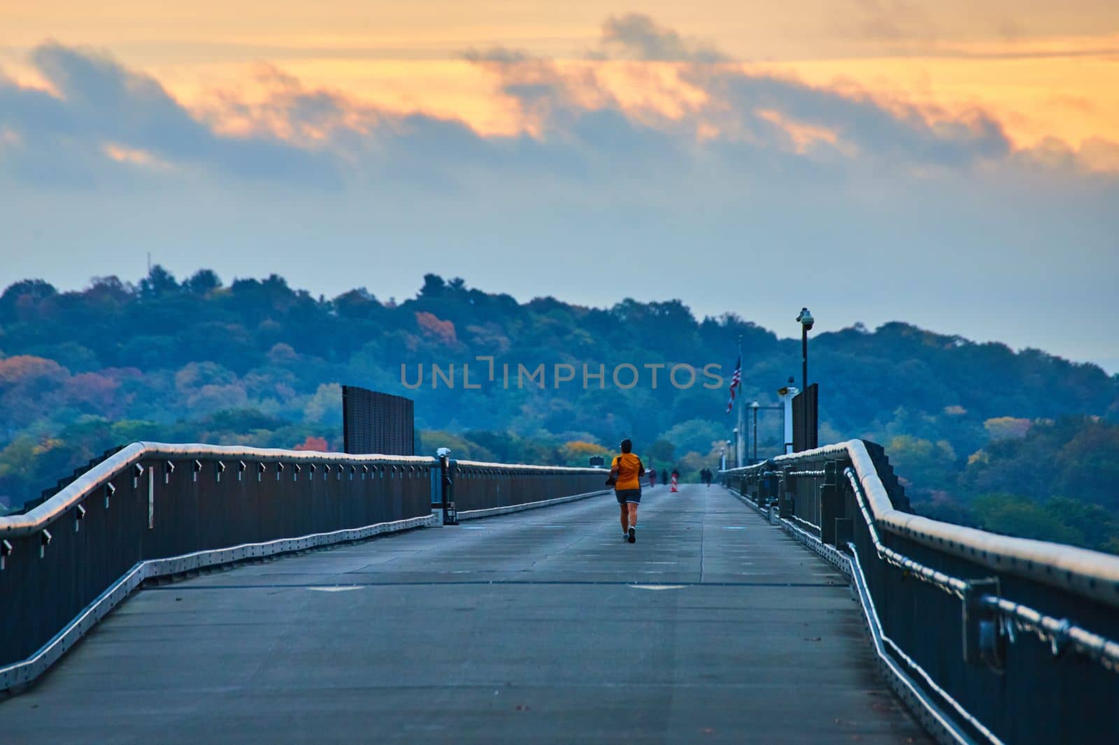 Huge cement bridge walkway with joggers during morning light by njproductions