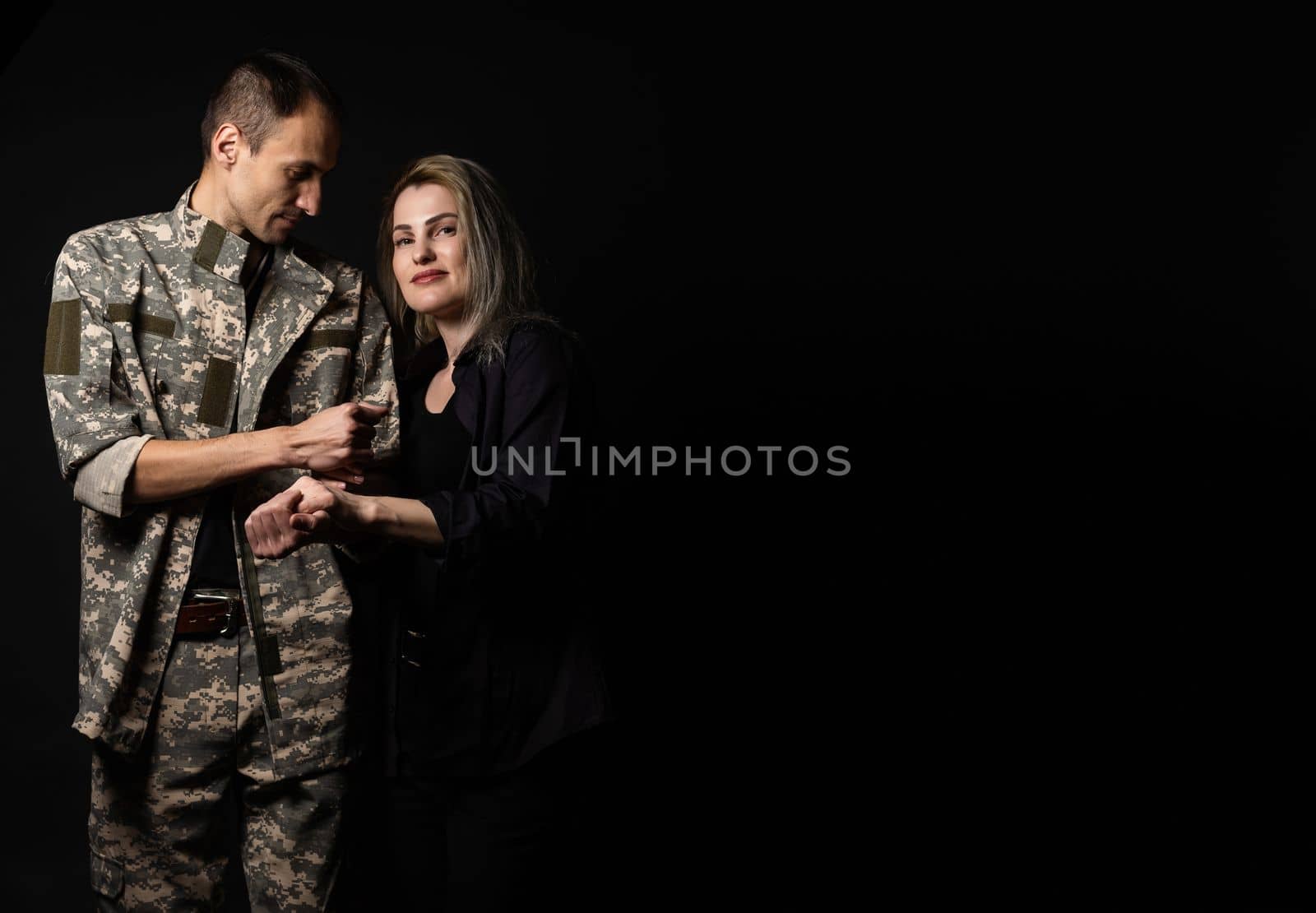 military man and his wife on a black background.