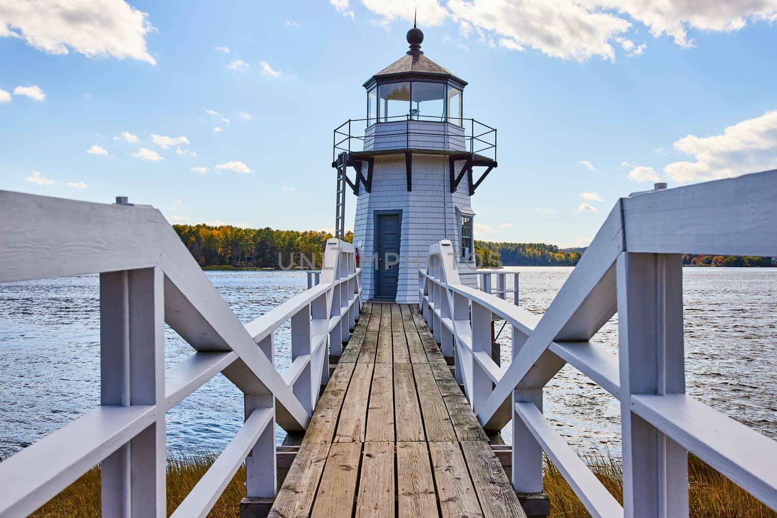 White Maine lighthouse with wood boardwalk and railing by njproductions