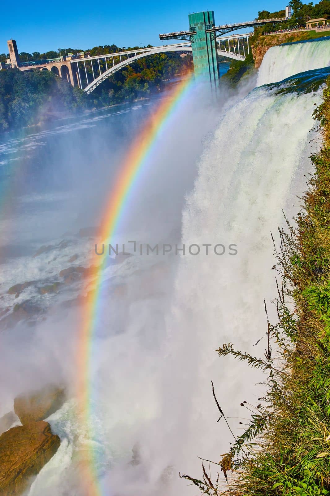 Image of Misty American Falls and Rainbow Bridge with stunning rainbow at Niagara Falls