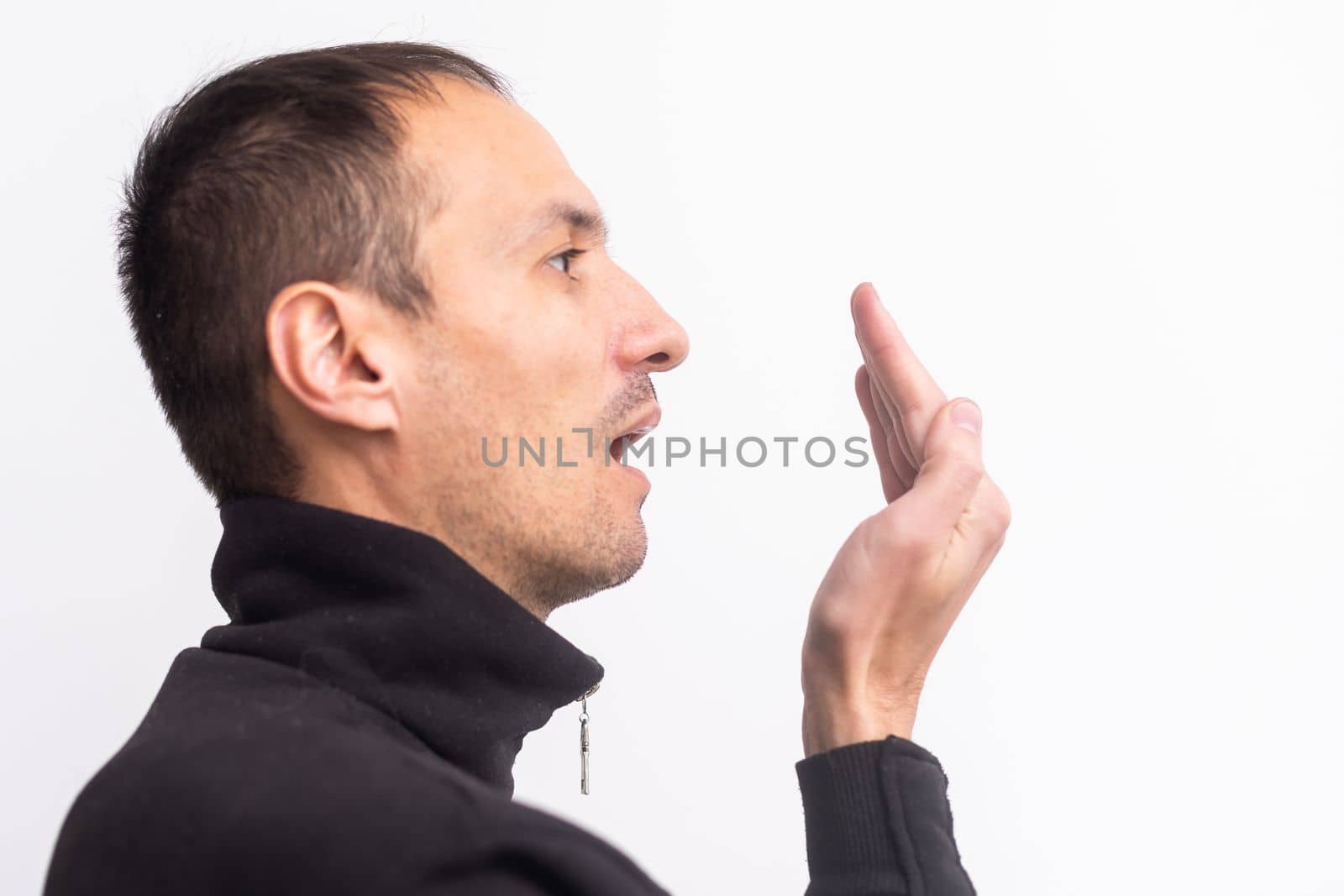 Man checks his breath with his hand. The concept of halitosis
