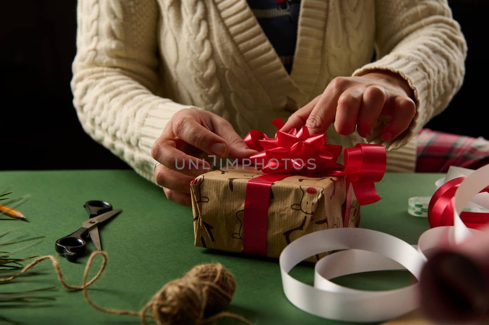 Close-up woman tying red bow, wrapping Christmas gift box. Packing present. Boxing day. Happy holiday present, surprise. Magic time. Celebration winter event. Handwork art craft. New Year preparations