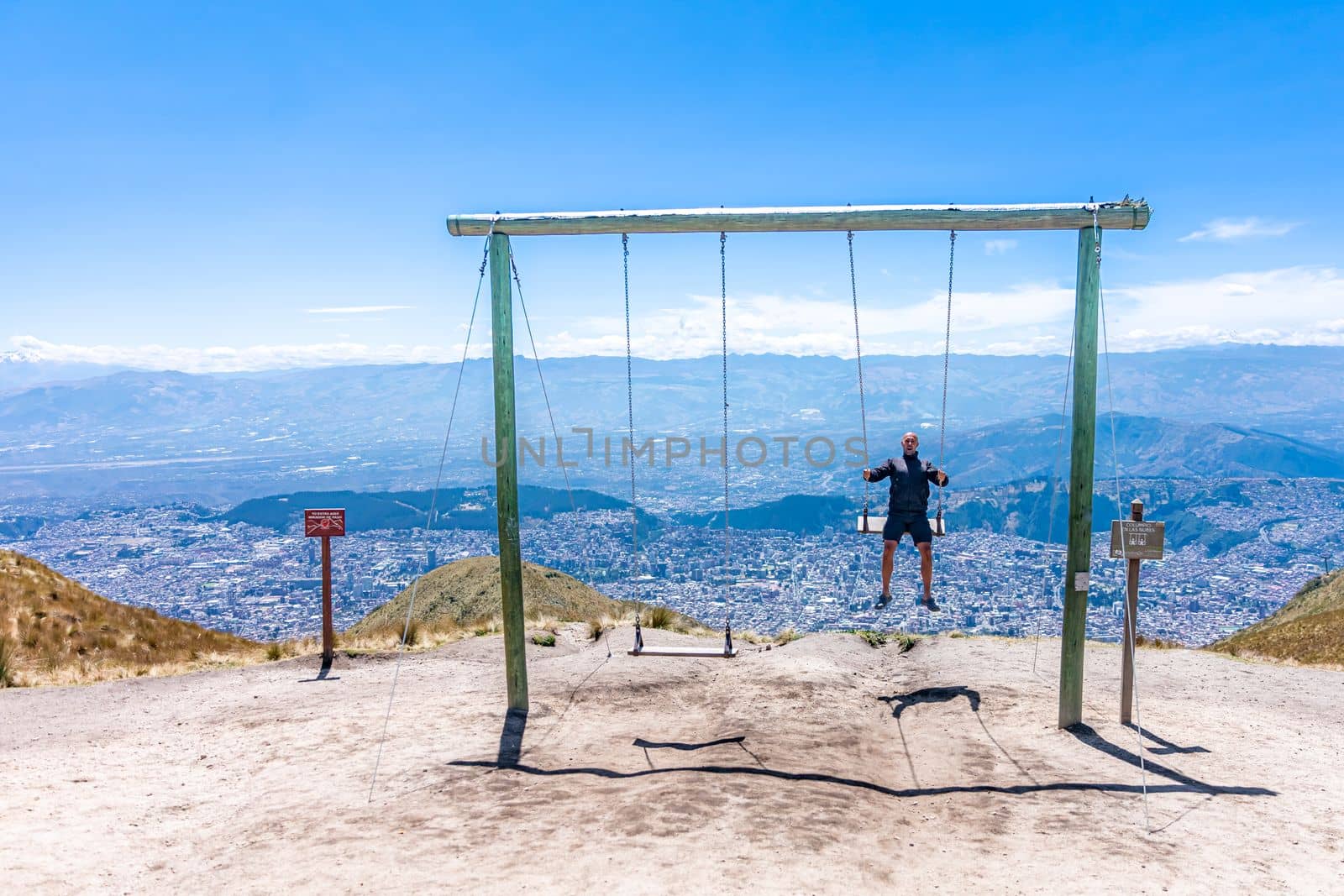 man on a swing at a viewpoint in the mountains by Edophoto