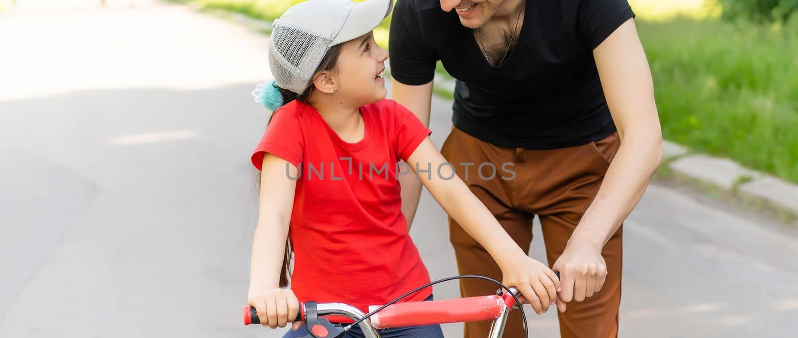 happy family father teaches child daughter to ride a bike in the Park in nature by Andelov13
