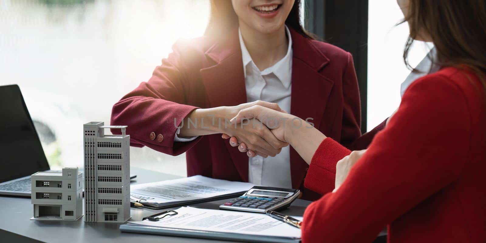 Real estate agents shake hands after the signing of the contract agreement. Business people shake hands. Real estate concept by itchaznong