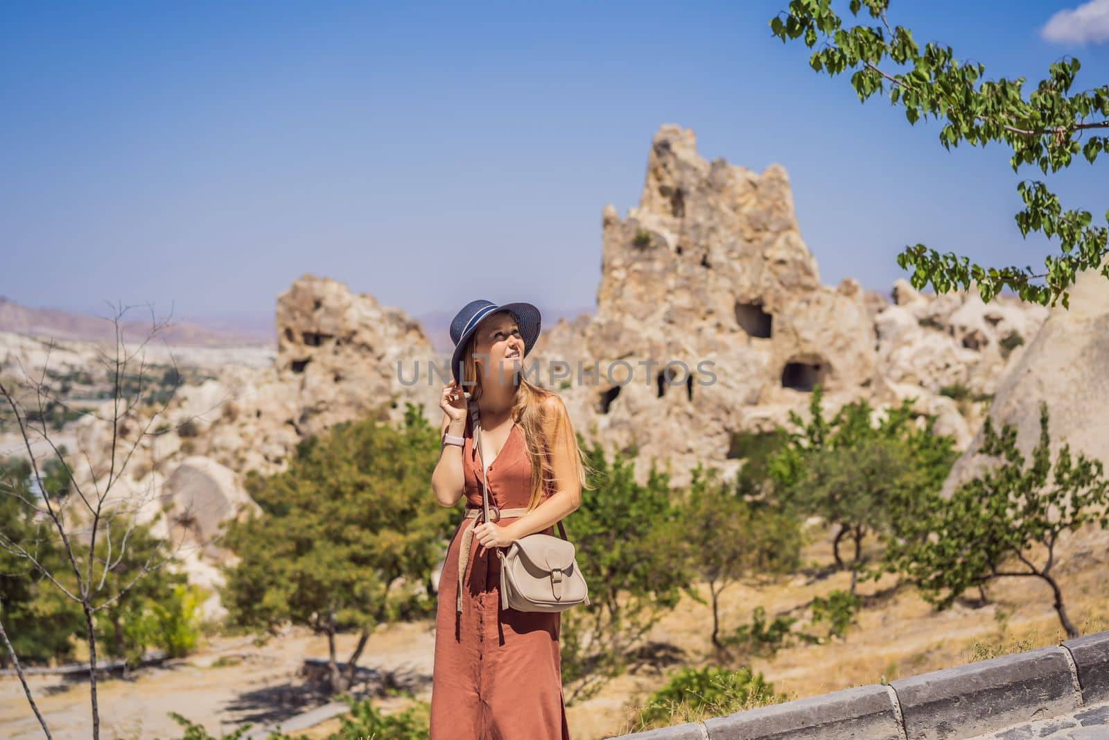Young woman exploring valley with rock formations and fairy caves near Goreme in Cappadocia Turkey.