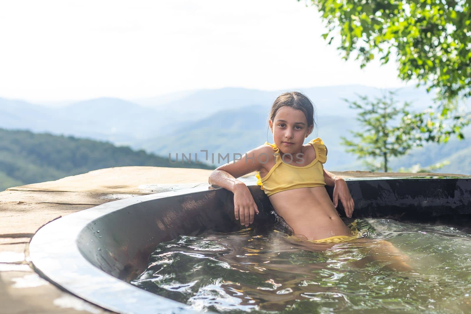 little girl in a hot tub in the mountains, summer.