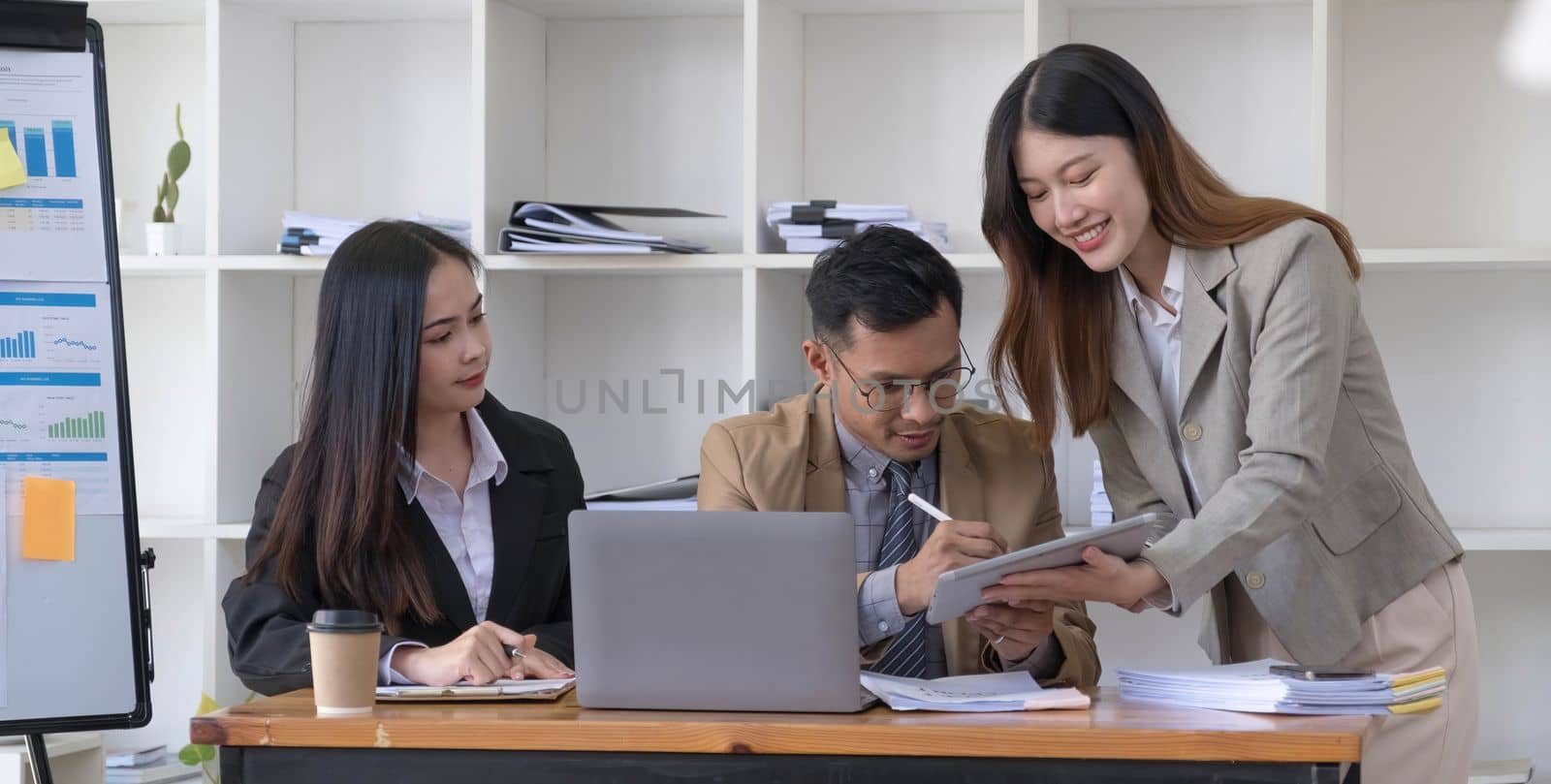 Group of young asian business people in smart casual wear working together in creative office using laptop...