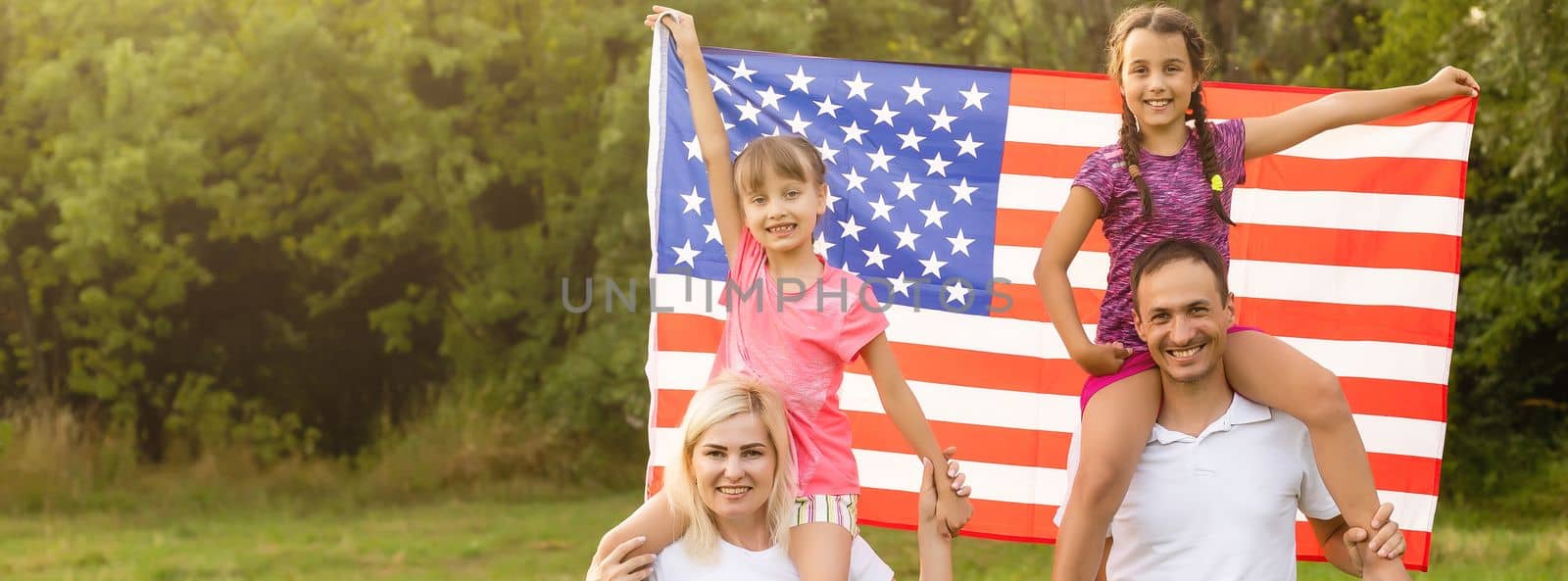 happy family with the flag of america USA at sunset outdoors.