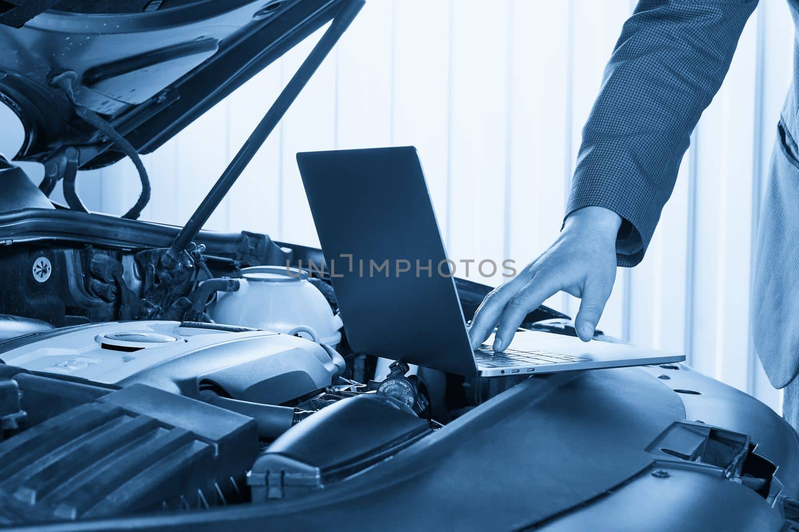 Services car engine machine concept, Automobile mechanic repairman checking a car engine with using computer diagnostics while repairing, car service and maintenance.