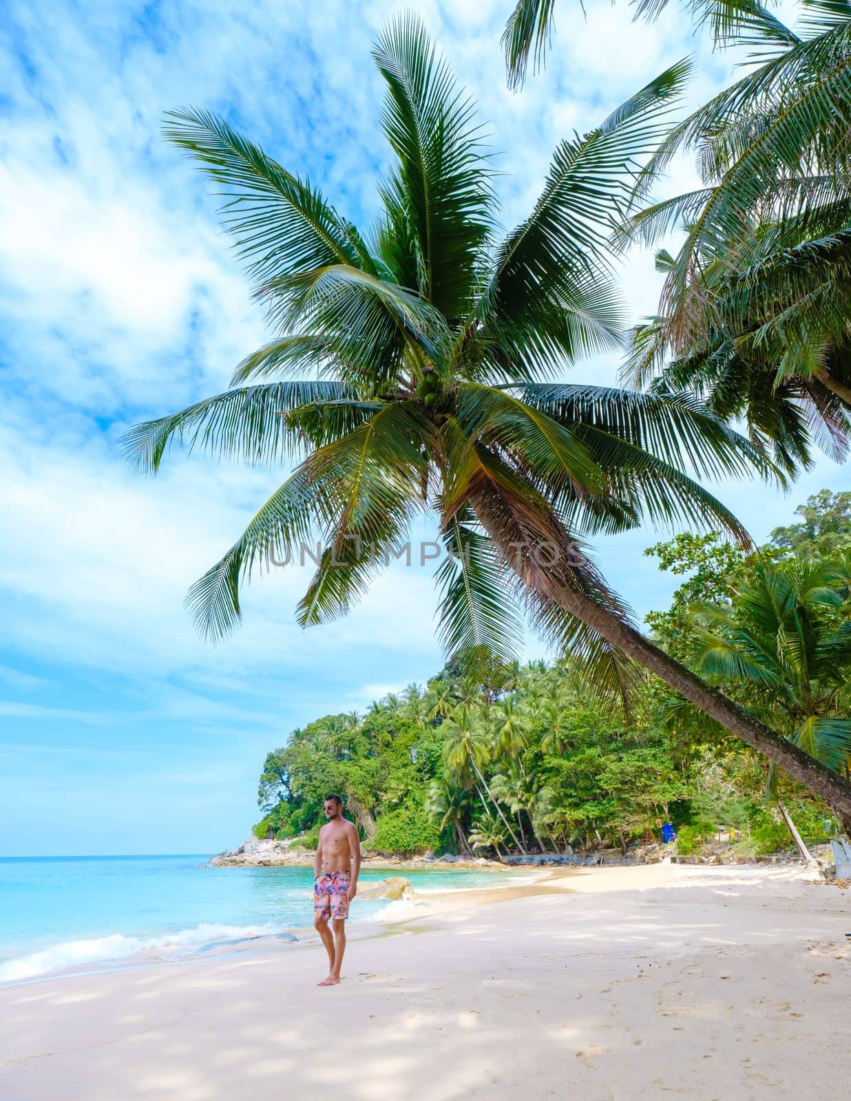 young men walking on the beach at the tropical Surin beach Phuket in Southern Thailand.