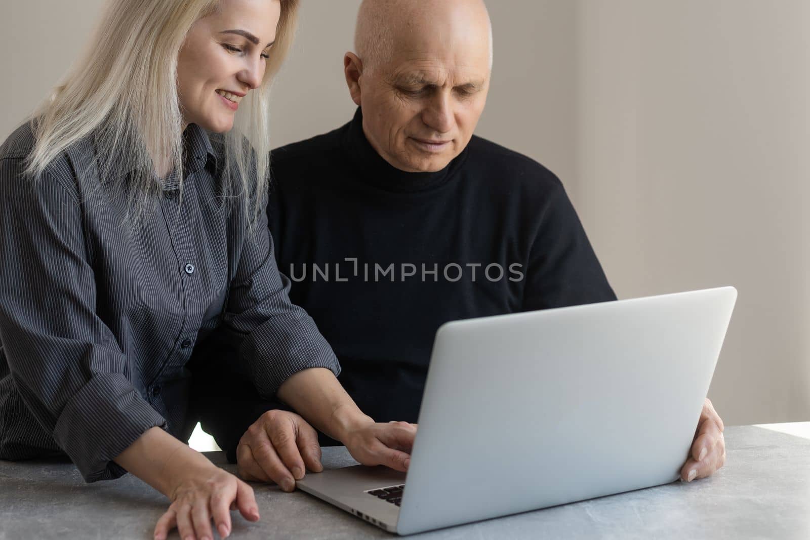 Happy smiling young girl teaching and showing new computer technology to her grandfather