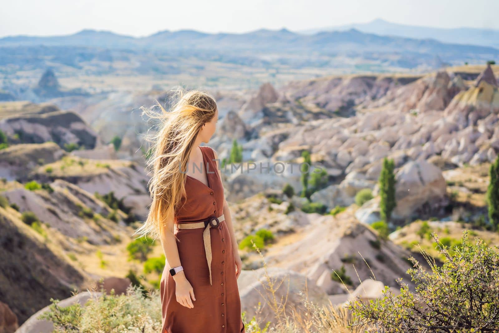 Young woman exploring valley with rock formations and fairy caves near Goreme in Cappadocia Turkey.