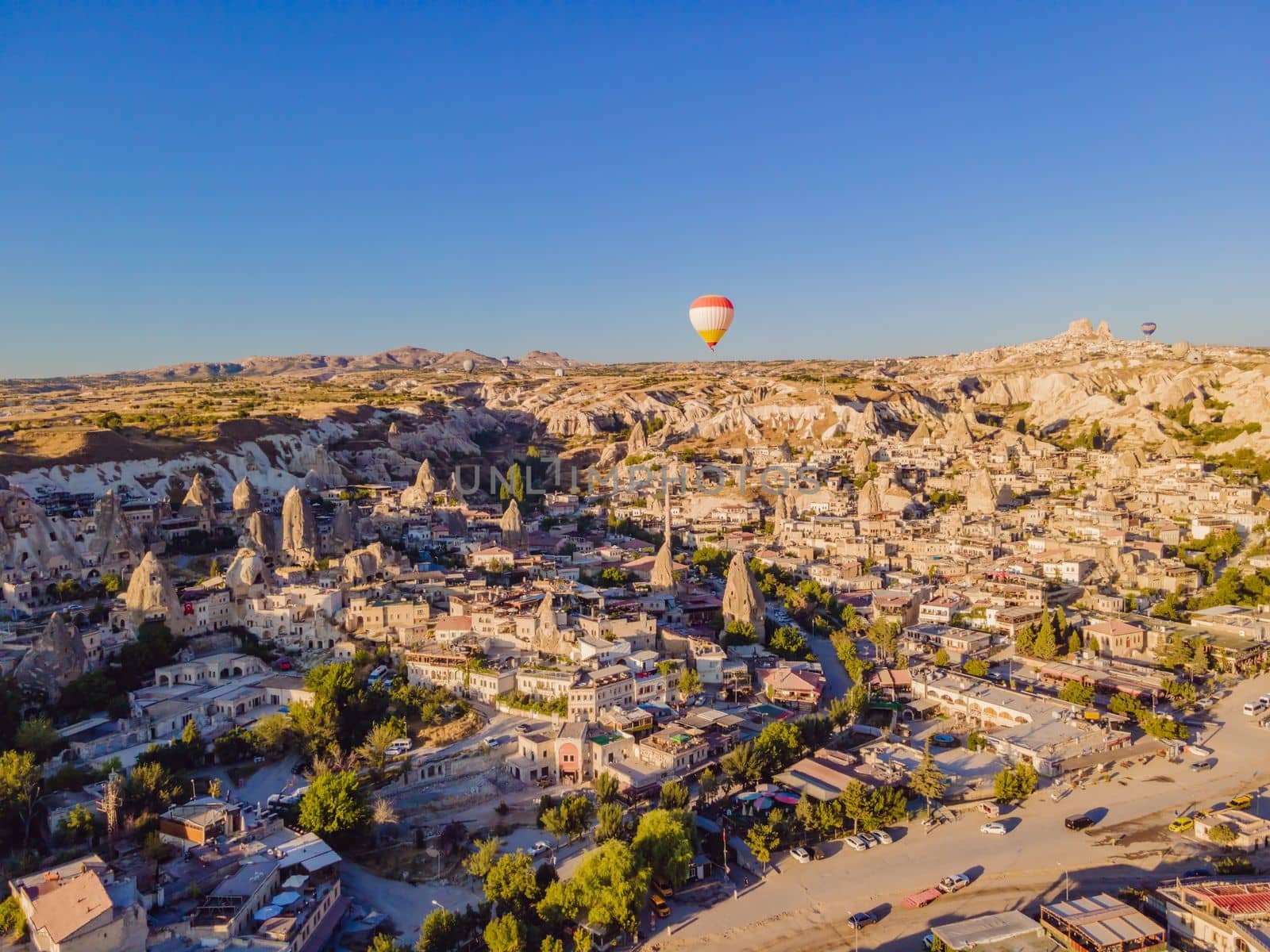 Colorful hot air balloons flying over at fairy chimneys valley in Nevsehir, Goreme, Cappadocia Turkey. Spectacular panoramic drone view of the underground city and ballooning tourism. High quality.