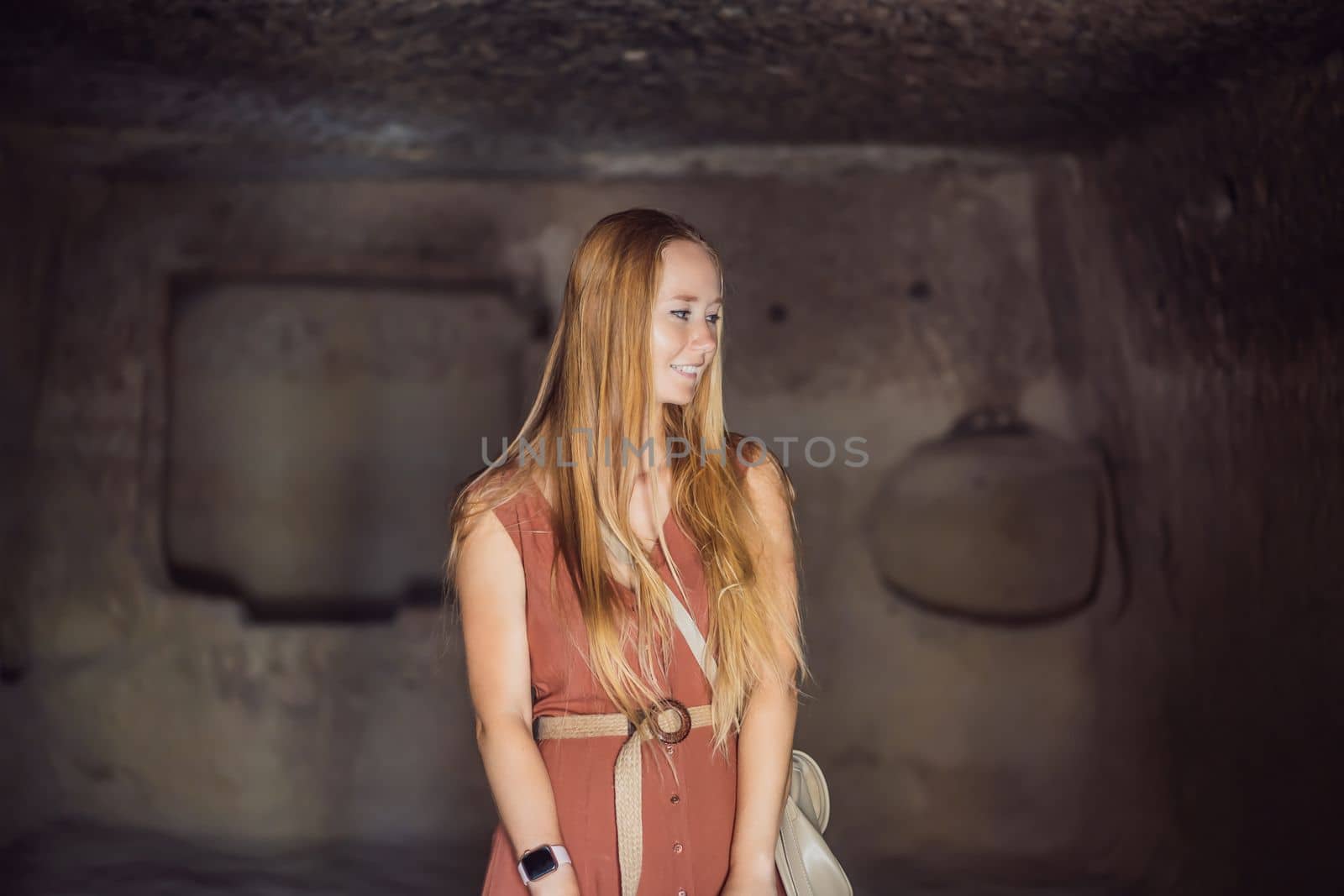 Young woman exploring valley with rock formations and fairy caves near Goreme in Cappadocia Turkey.