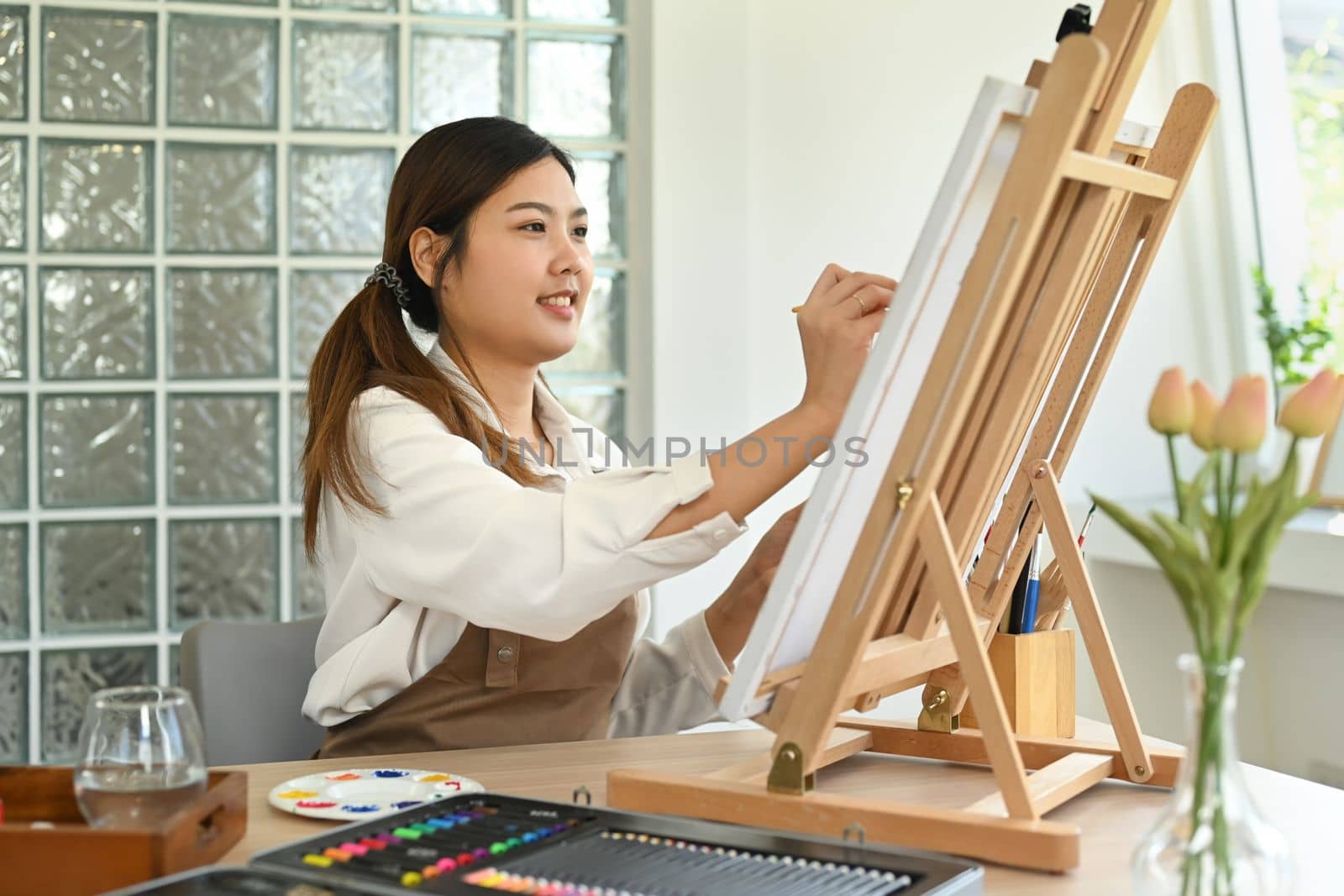 Attractive female artist painting with watercolor on canvas in art workshop. Art, creative hobby and leisure activity concept by prathanchorruangsak