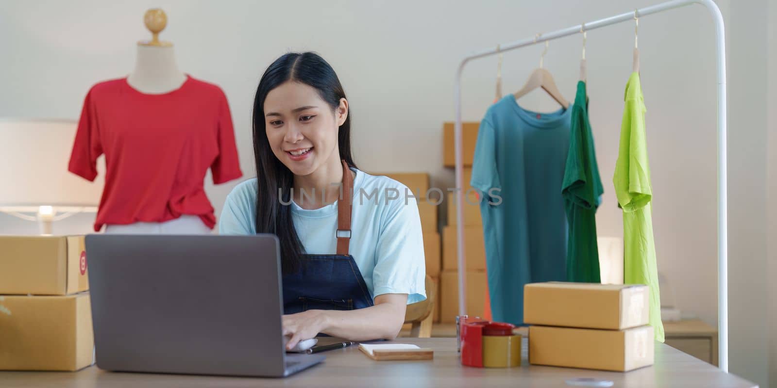 Asian Woman fashion designer cloth tailor creative working for new collection. Happy online store owner preparing an order for shipping by itchaznong