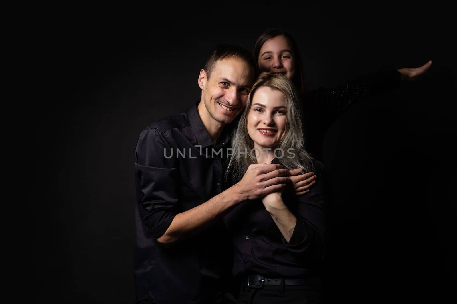 happy family mother, father, daughter on a black background.