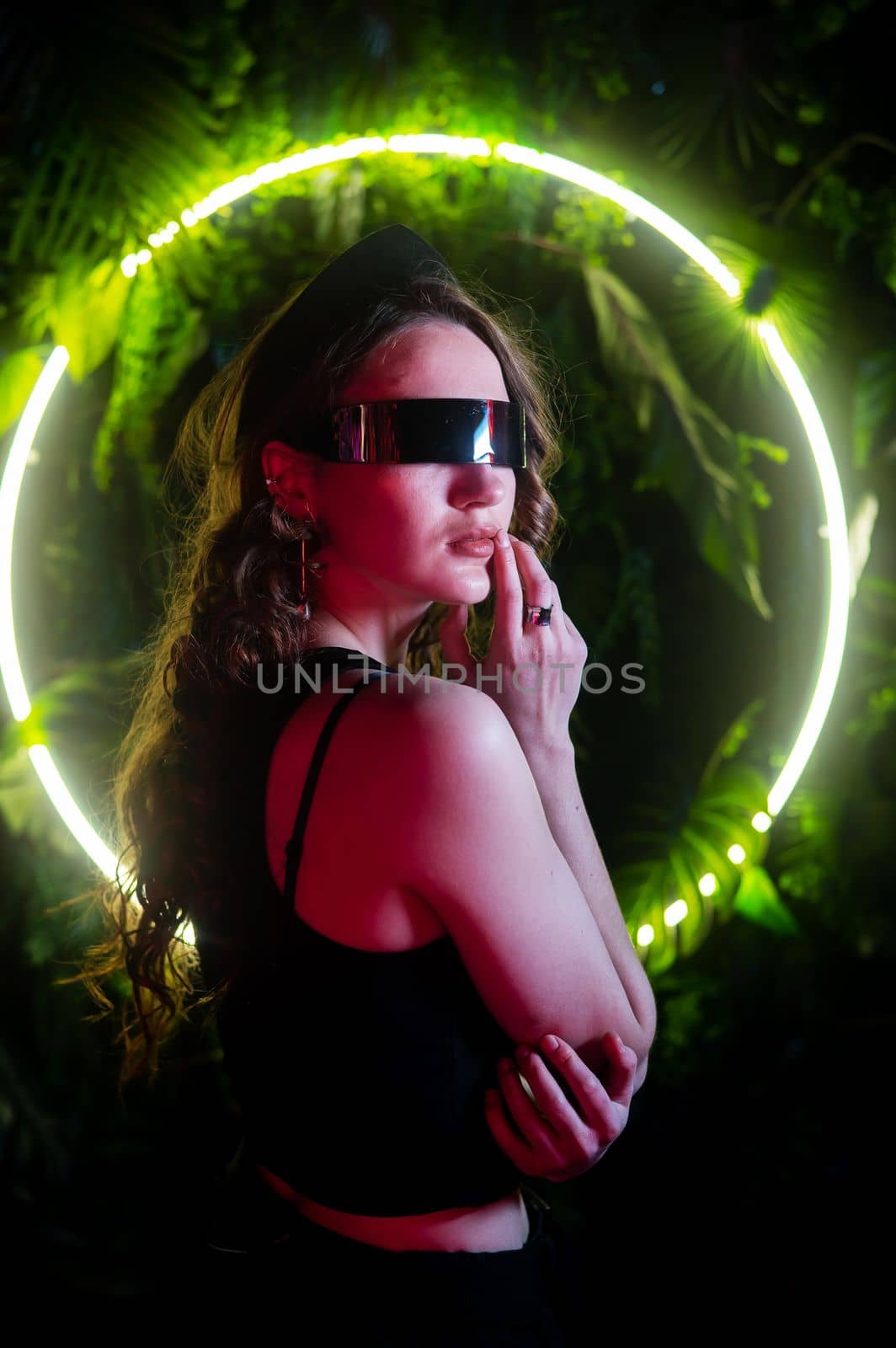 Caucasian woman in panoramic sunglasses against the background of an annular neon lamp in plants