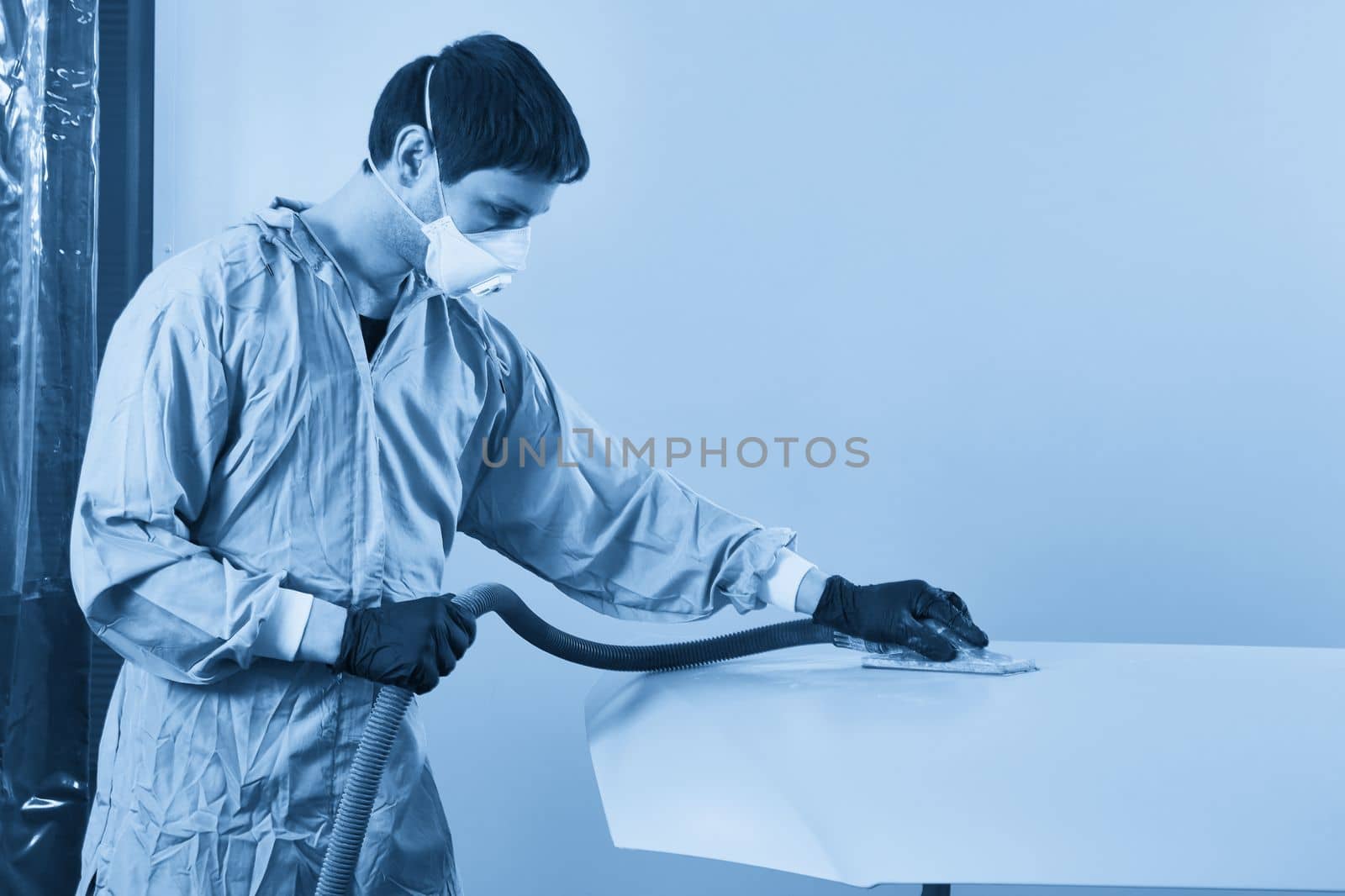 Auto mechanic buffing and polishing car in auto repair shop