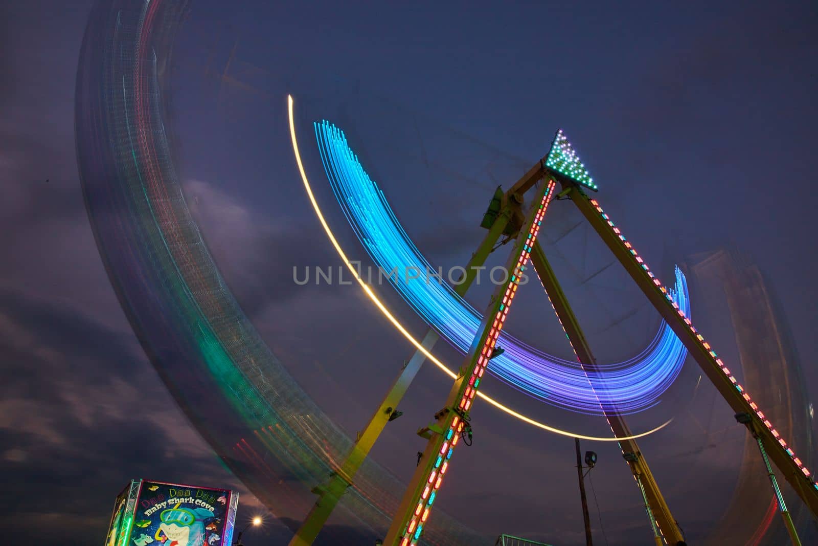 Image of Dusk carnival ride swinging with blurred lights at county fair