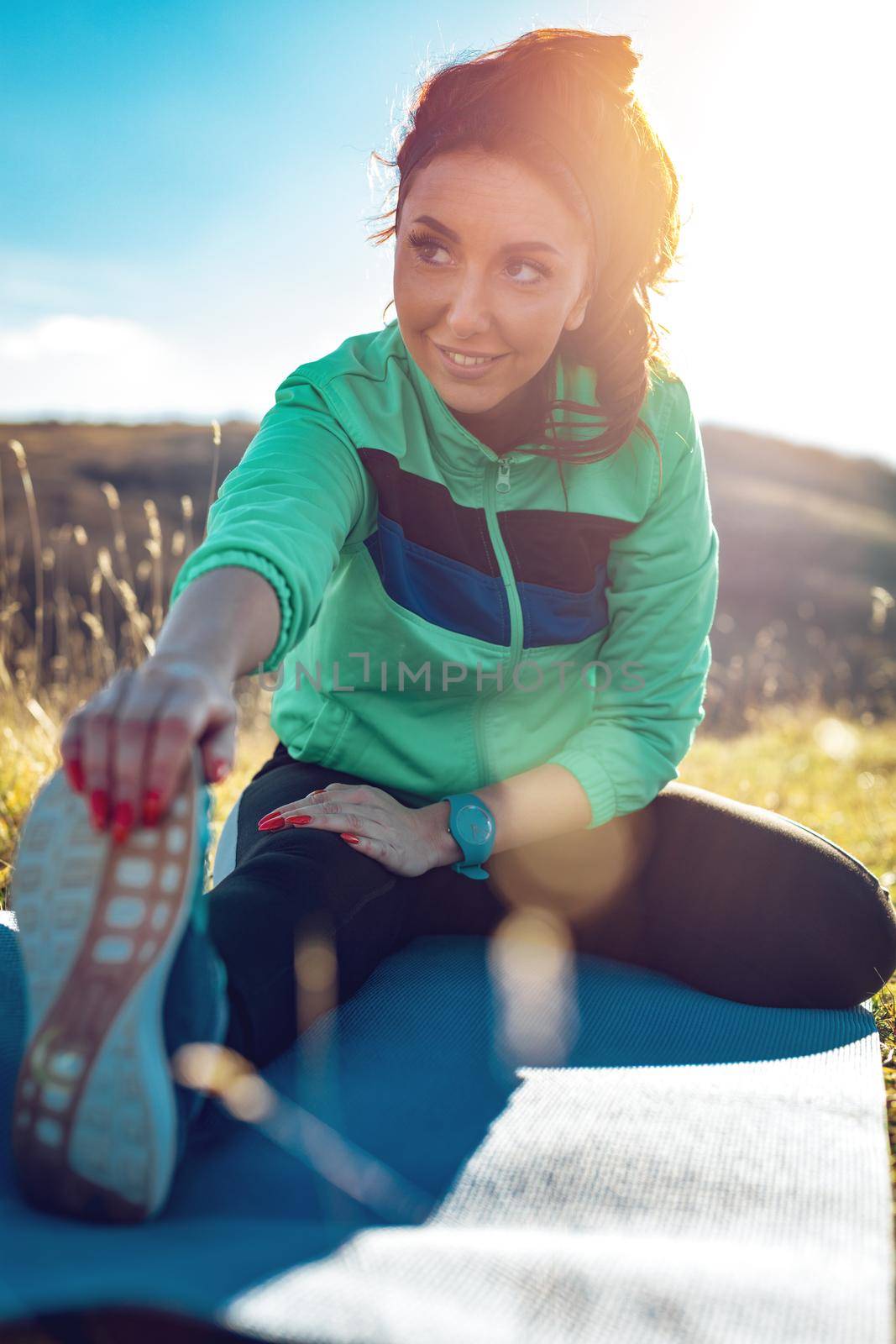 Young fitness woman doing stretching exercise after jogging in the nature.