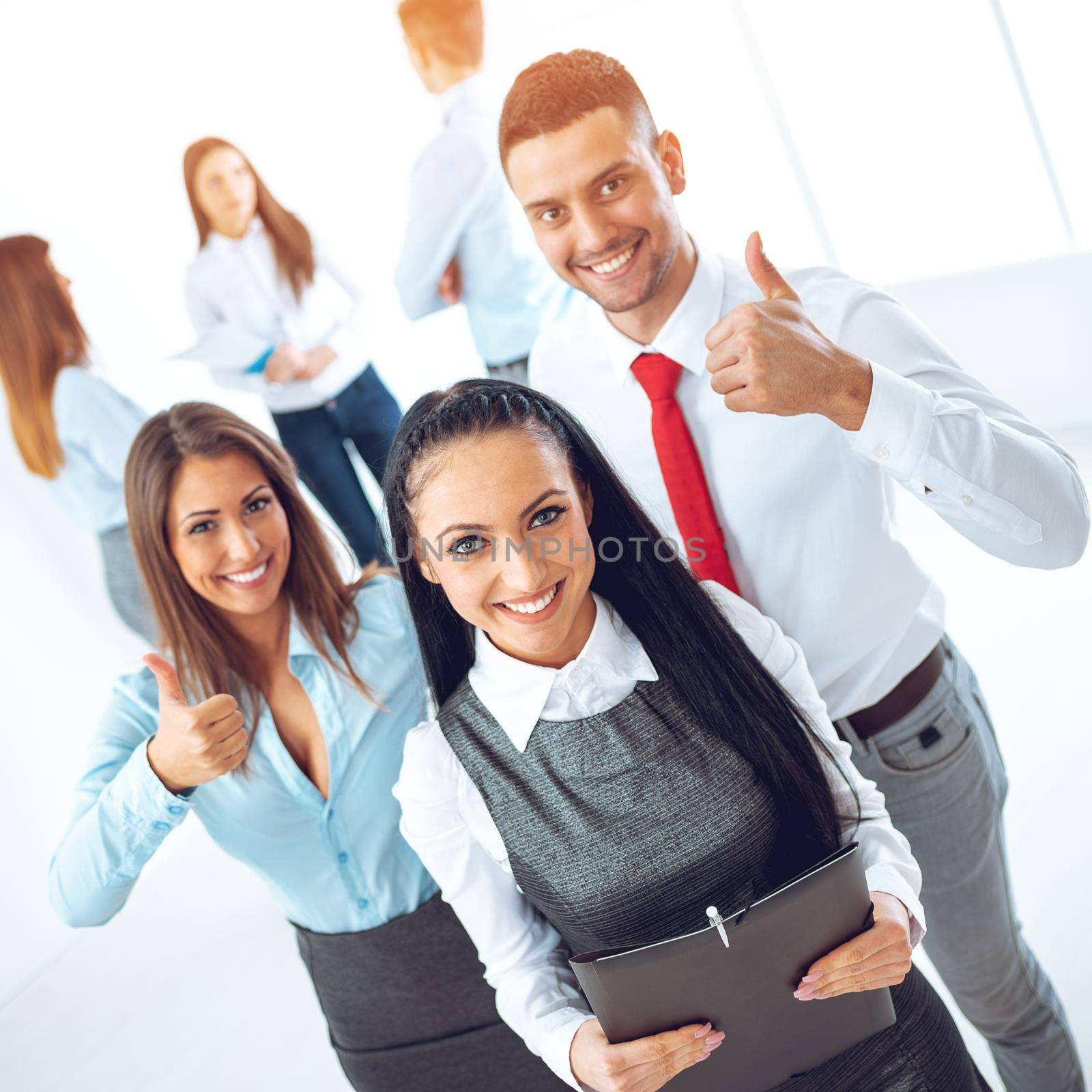 Successful young businesswoman standing proudly with her young business team and looking at the camera.