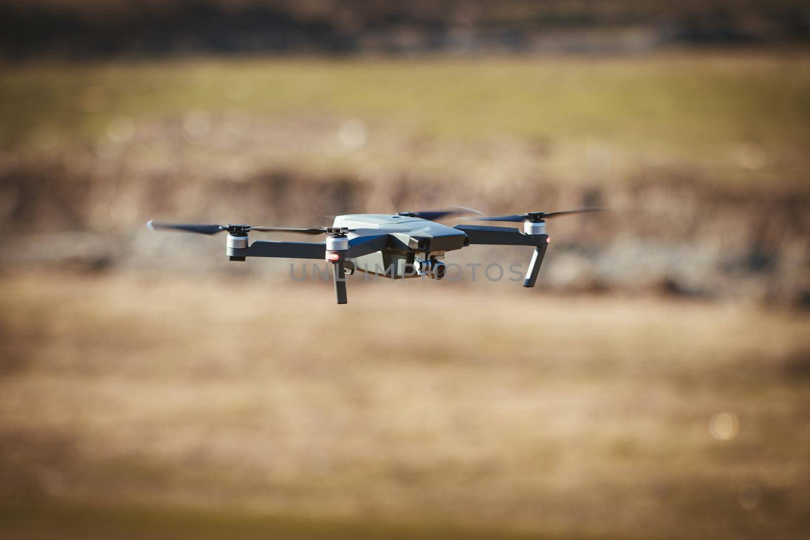 Drone take off from land and flying above field, for take aerial photo.