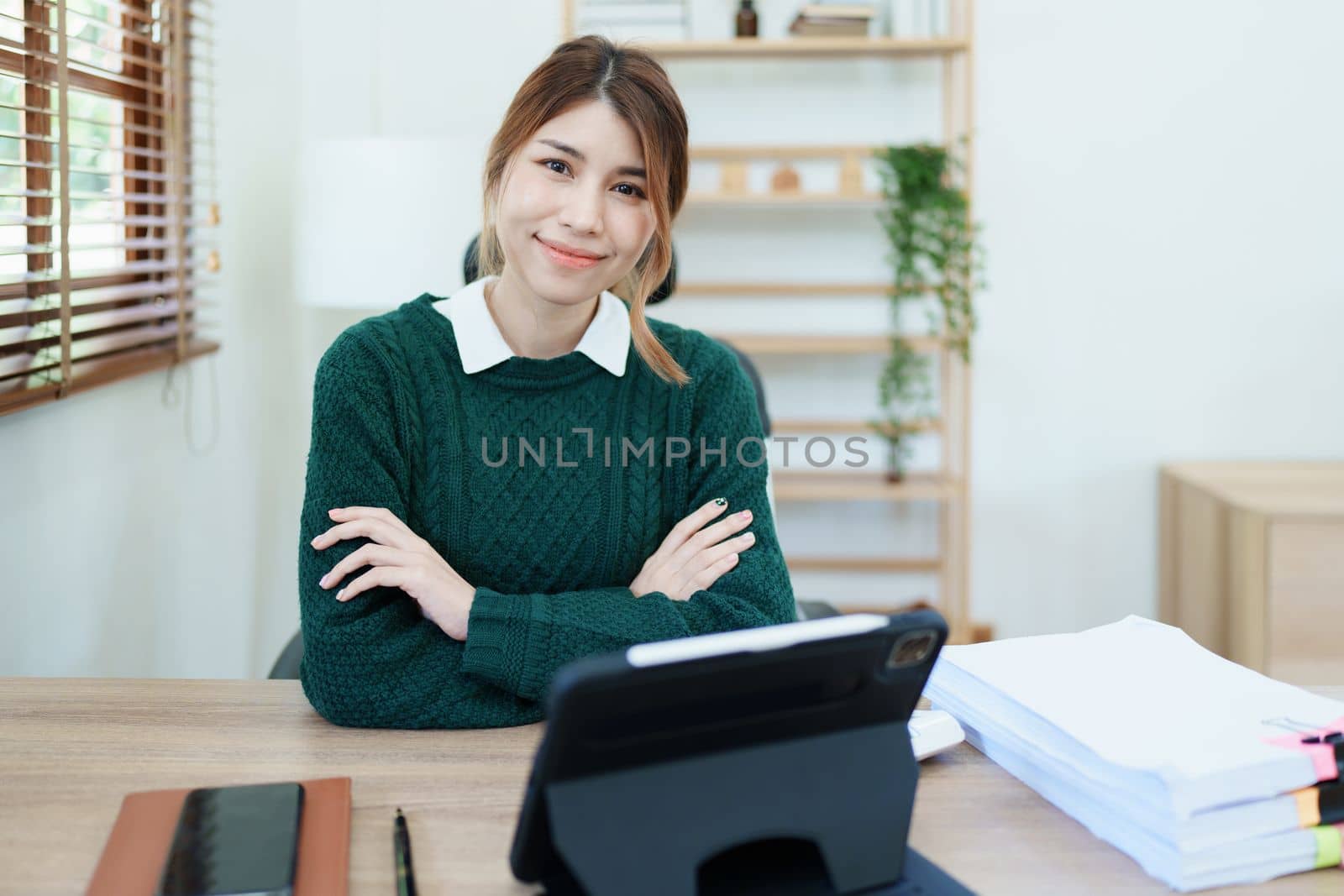 Portrait of a woman business owner showing a happy smiling face as he has successfully invested her business using computers and financial budget documents at work by Manastrong