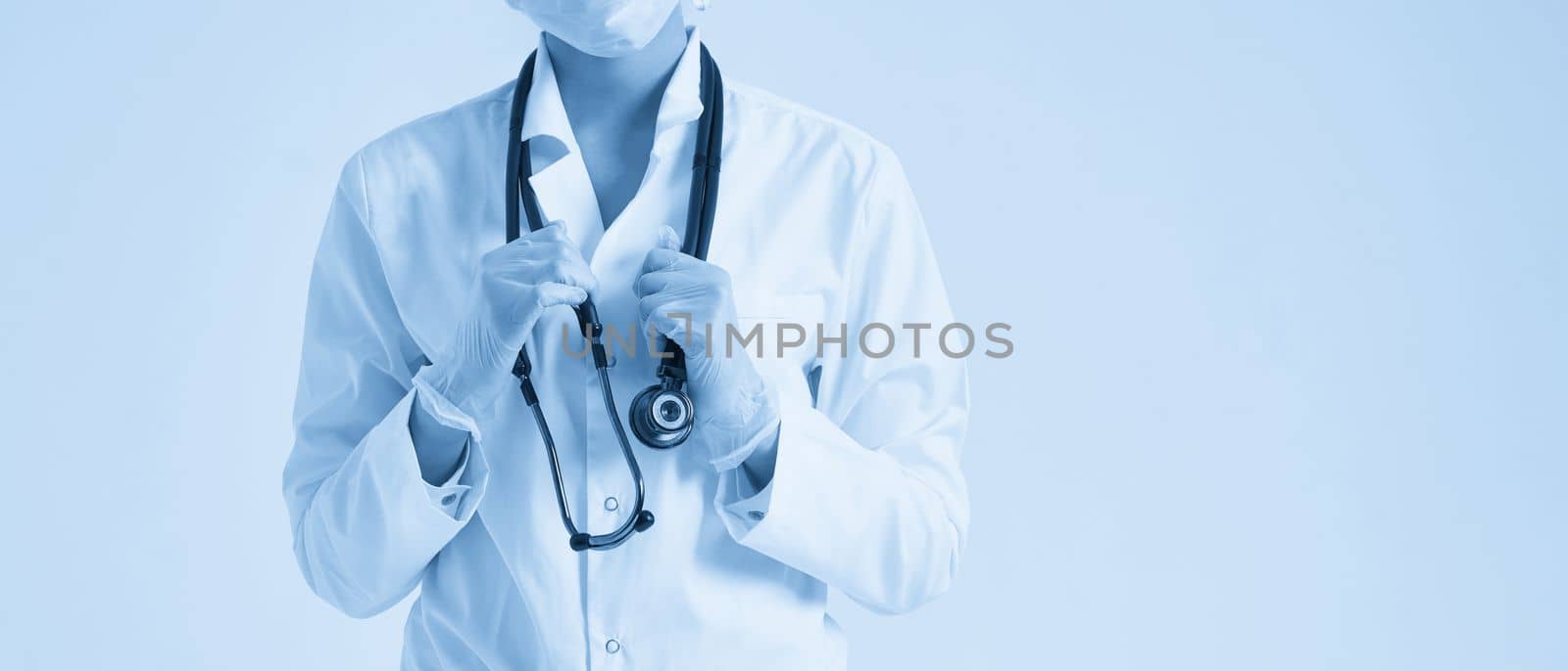 Young female doctor holding stethoscope hanging on her neck, studio shot over white background with copy space by Mariakray