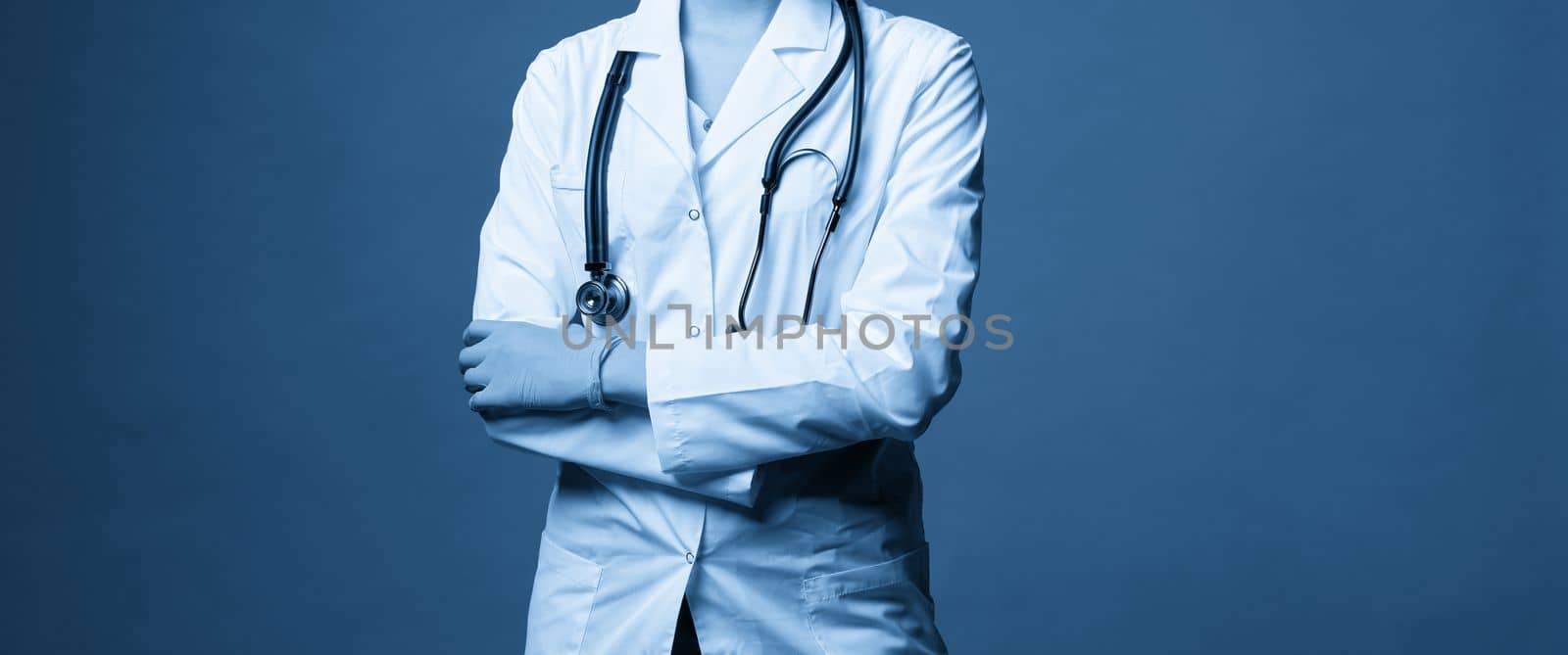 Young doctor with stethoscope against dark blue background, studio shot with copy space by Mariakray