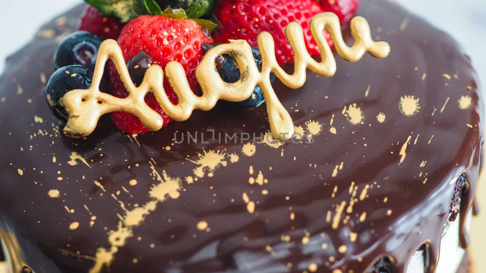 dark chocolate drips birthday sweet cake, fresh fruits Raspberry strawberry blueberry cranberry on top, decorated with golden edible paint