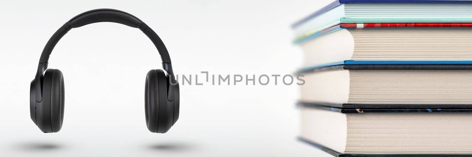 Audiobooks. Stack of books and headphones with space for copy space. Choice between books and audiobooks. by SERSOL