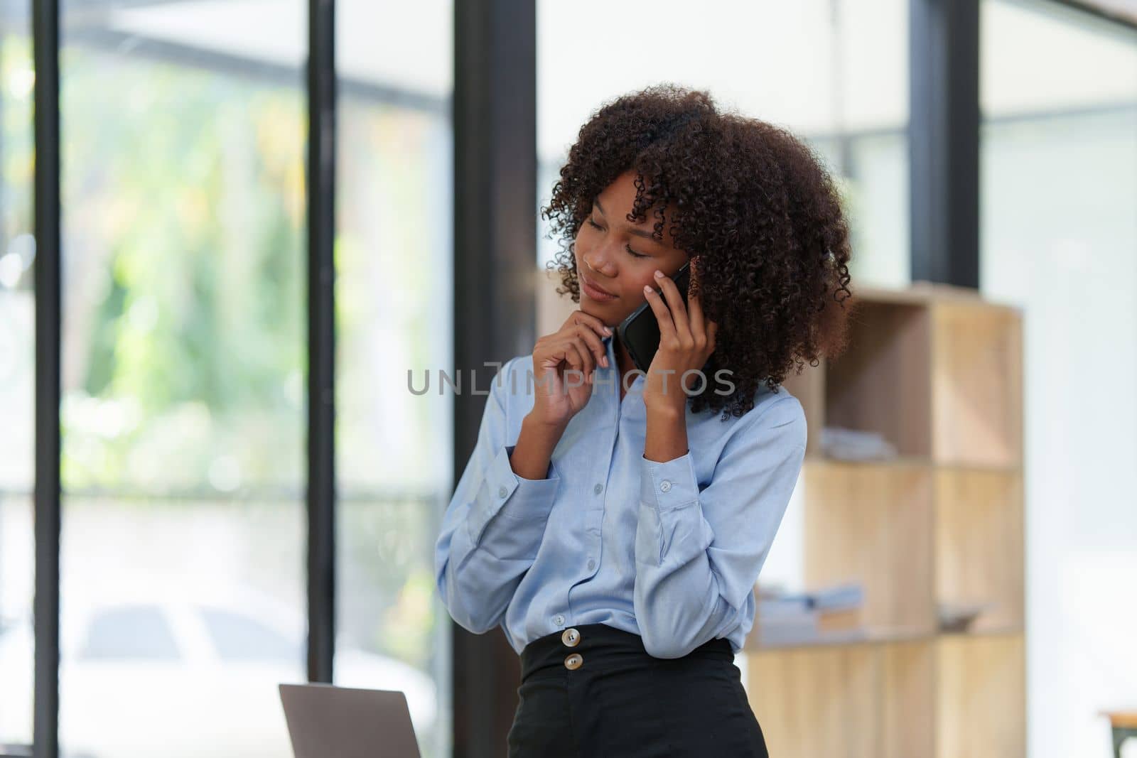 Business black woman having phone conversation with client in office. African american young woman using smart phone.