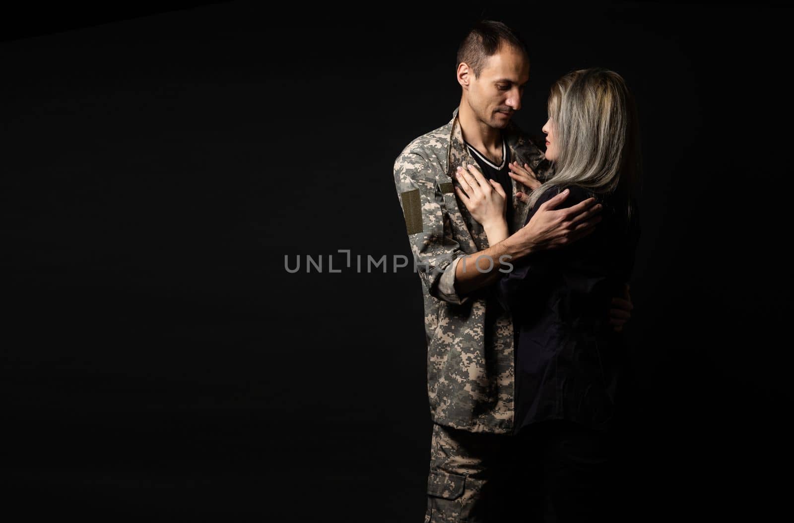 Happy woman hugging his husband came back from army. Smiling cheerful caucasian girlfriend embracing a soldier