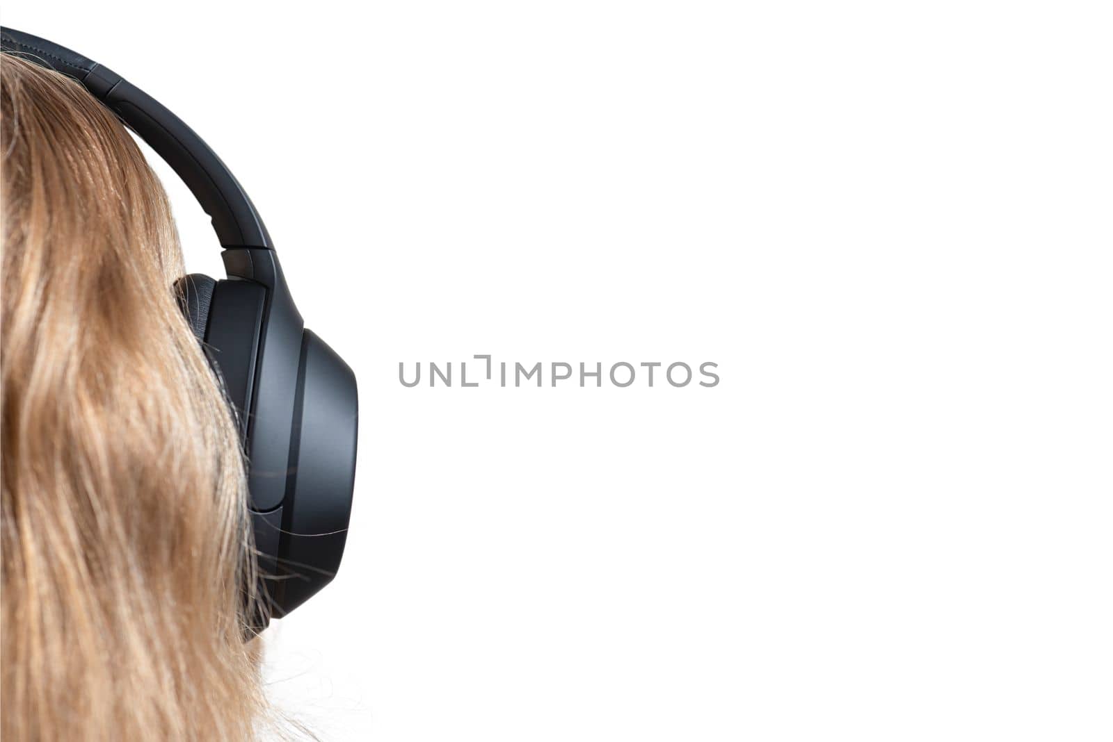 Woman in headphones isolated on white. Black headphones on a woman's head. Head of a fair-haired woman in headphones, rear view close-up