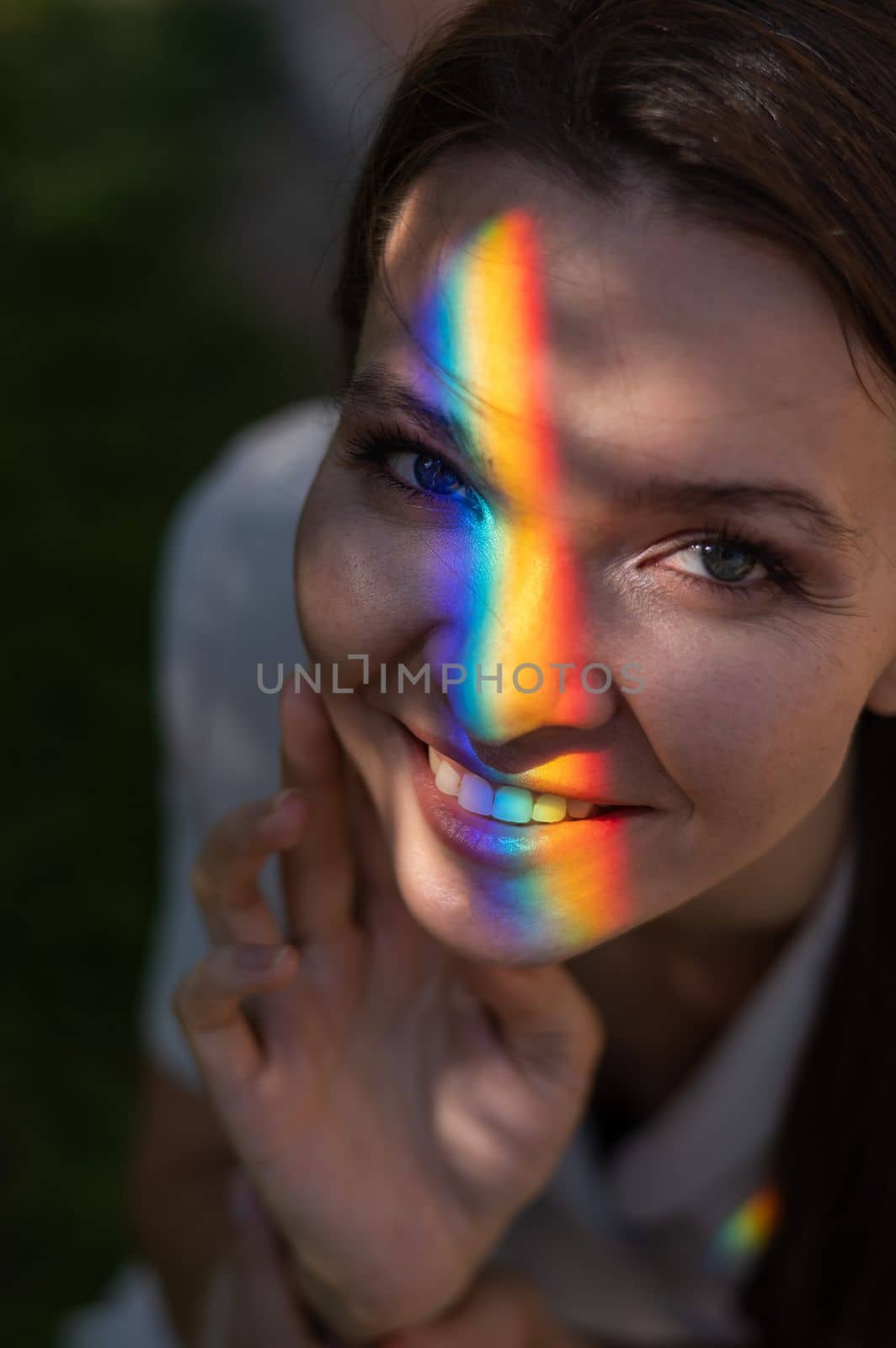 Portrait of caucasian woman with rainbow beam on her face outdoors