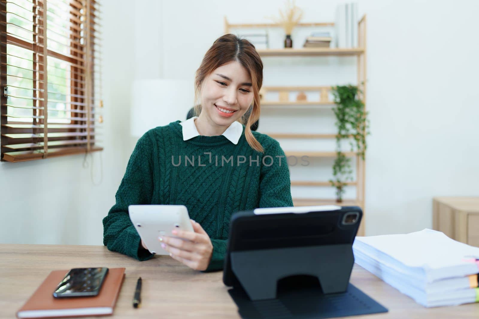 business owner or Asian female marketers are using calculator to calculate and tablet computer in office work.