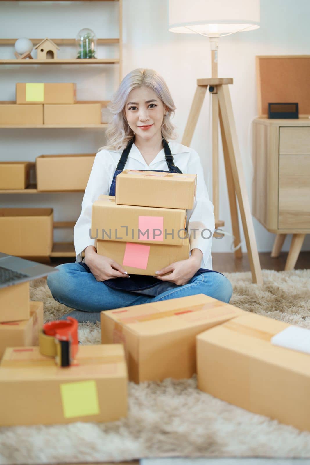 Starting small business entrepreneur of independent Asian woman smiling using computer laptop with cheerful success of online marketing package box items and SME delivery concept.