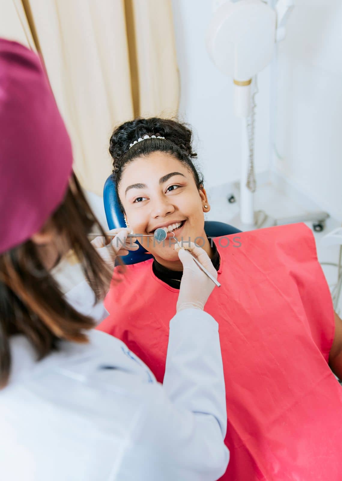 Patient lying on chair smiling at dentist, Close up of female dentist doing dental checkup to smiling patient, Dentist doing dental checkup to female patien by isaiphoto